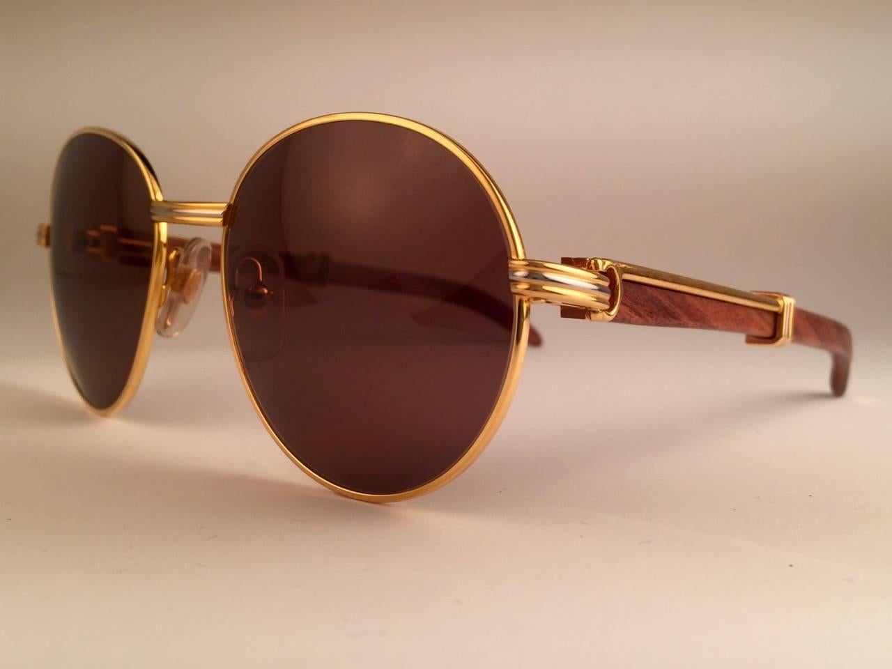 New original 1990 Cartier Bagatelle Wood Sunglasses from the coveted Precious Wood series with palisander wood temples and honey brown (uv protection) lenses. 
The frame has the front and sides in yellow and white gold. 
All hallmarks. gold Cartier
