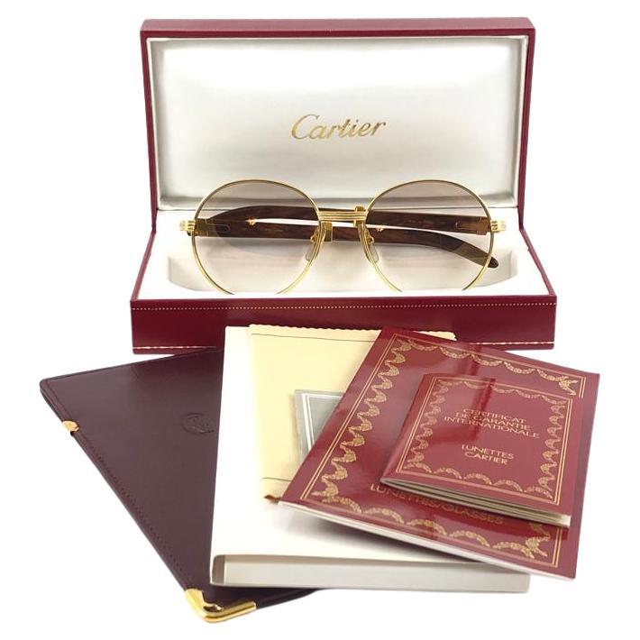 Neue original 1990 Cartier Bagatelle Wood Sonnenbrille aus der begehrten Precious Wood Serie mit Holzbügeln und leicht verspiegelten (uv-Schutz) Gläsern.
Der Rahmen ist auf der Vorderseite und an den Seiten in Gelb- und Weißgold gehalten. Alle