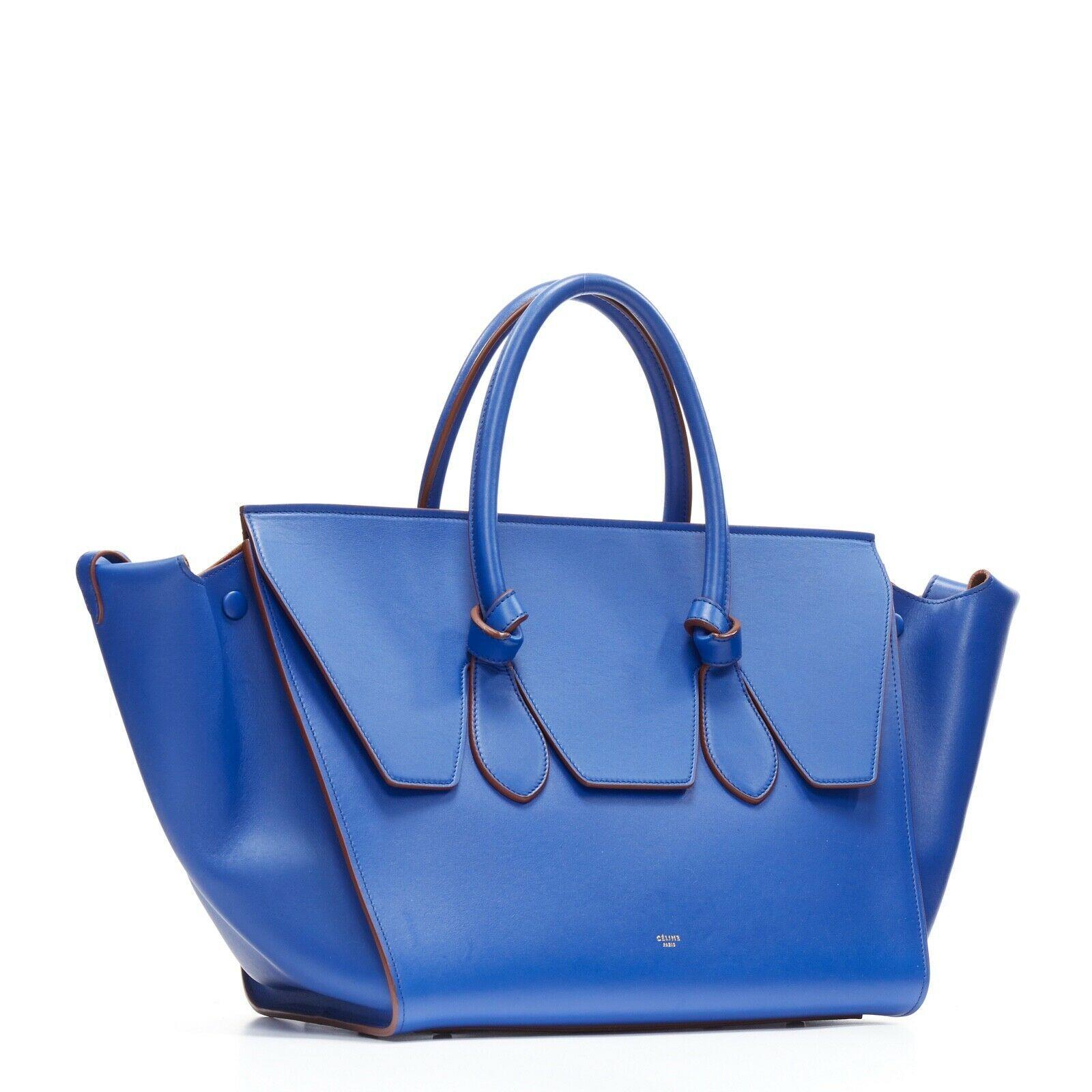new CELINE PHOEBE PHILO Knot cobalt blue calfskin large shopper tote bag full
CELINE BY PHOEBE PHILO
Knot bag . 
Tie knot handle design. 
Flared out sides with snap button closure to secure shape . 
Dangling straps that can be worn with the flared