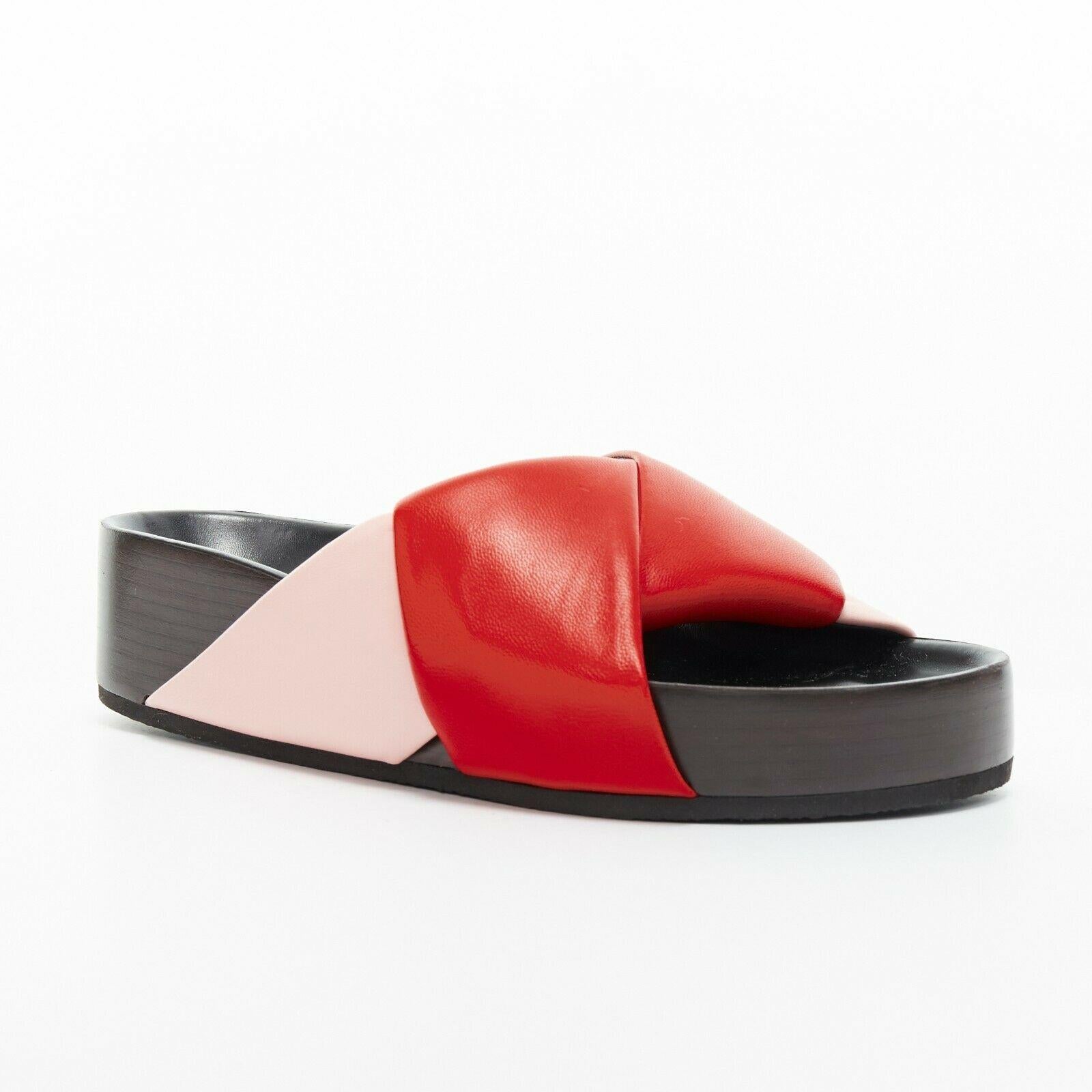 new CELINE PHOEBE PHILO red pink padded leather twist slides sandals EU36

CELINE BY PHOEBE PHILO
Light pink and red padded leather. Origami twist upper. strap. 
Open toe. Dark brown stacked wooden sole. 
Leather lining. Moulded footbed. Thick sole.