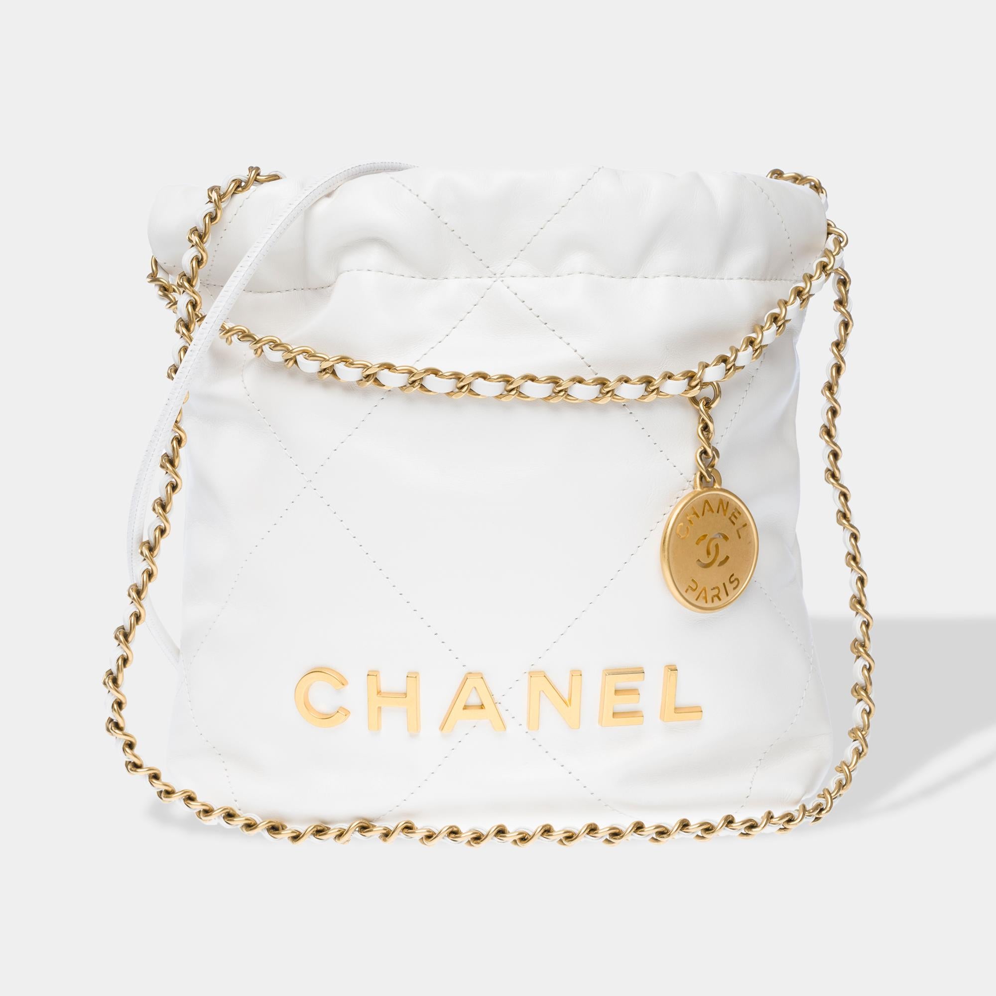 Precioso bolso Chanel 22 Mini acolchado de cuero blanco, con adornos de metal dorado, doble asa de cadena de metal dorado entrelazada con cuero blanco que permite llevarlo en la mano, al hombro o cruzado

Forro interior de lona beige, un bolsillo