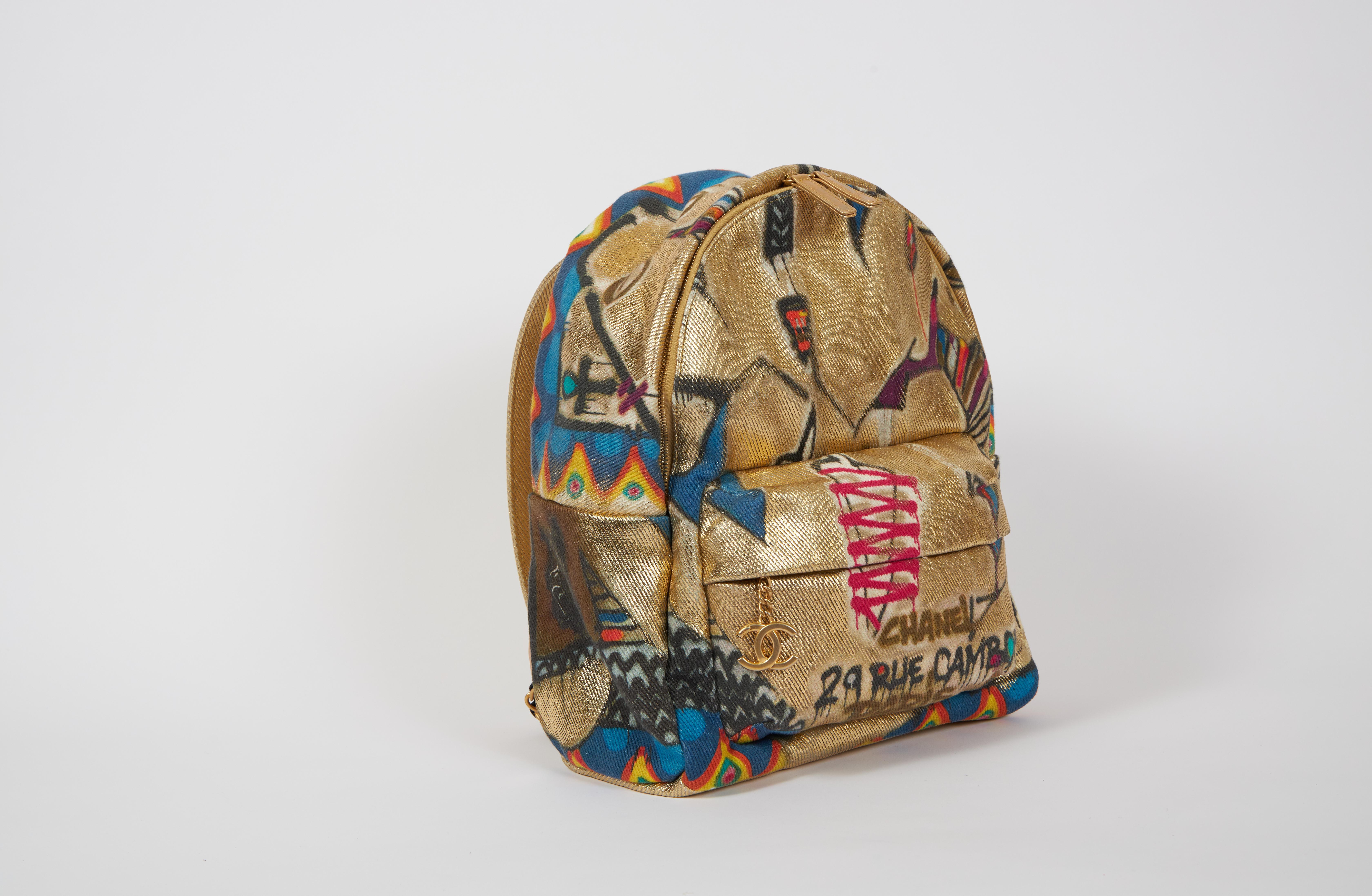 New Chanel limited edition graffiti-printed canvas backpack in gold. Comes with hologram, ID card, and original dust cover.