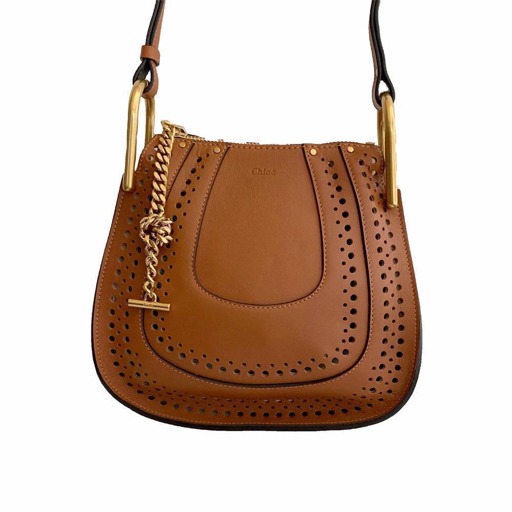 Circular perforations trace the rounded silhouette of this chic crossbody style, all rendered in smooth, buttery leather and finished with a brasstone chain accent.
Adjustable crossbody strap, 20