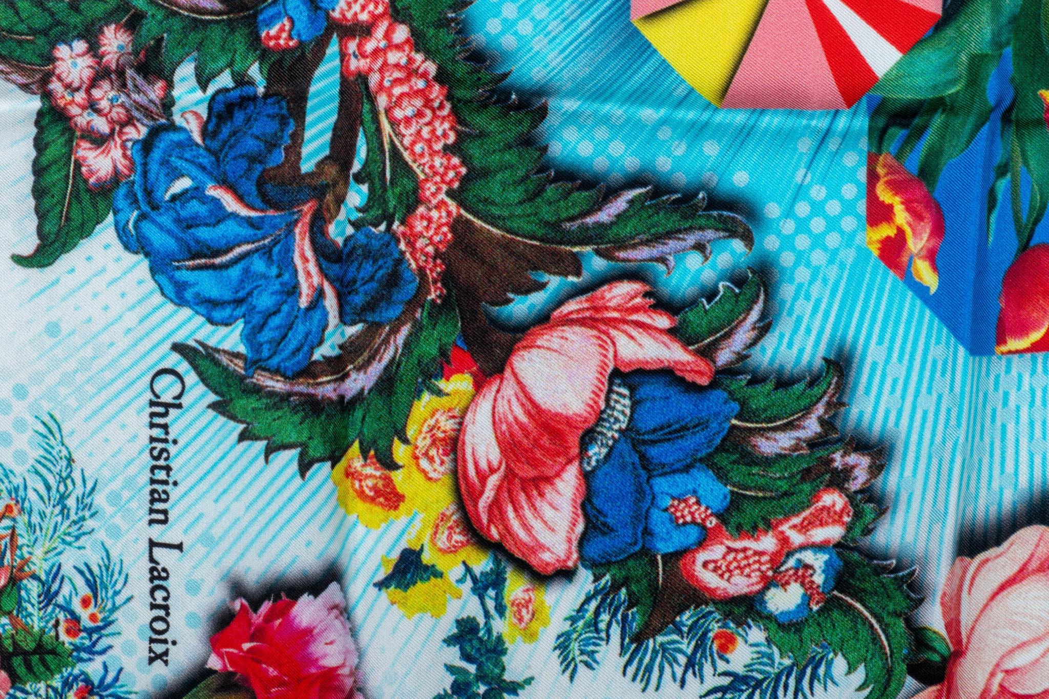 Petit foulard vintage Christian Lacroix 100% soie en état neuf. Fond bleu avec motif multicolore.