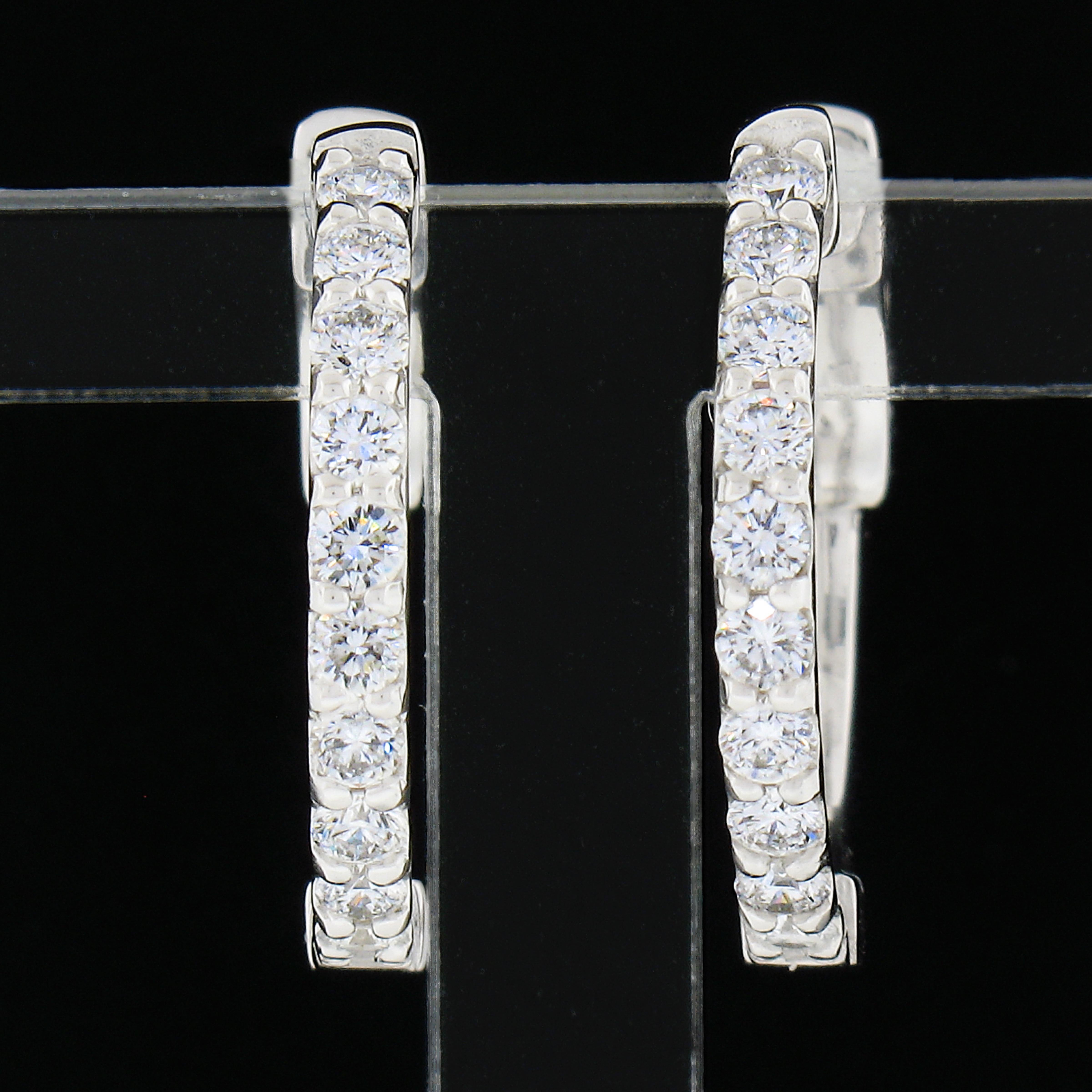 This classic pair of hoop earrings was newly crafted in solid 14k white gold and features exactly 0.60 carats of round brilliant cut diamonds. These fiery diamonds are neatly shared-prong set across the front side in sets of 10. They sparkle very