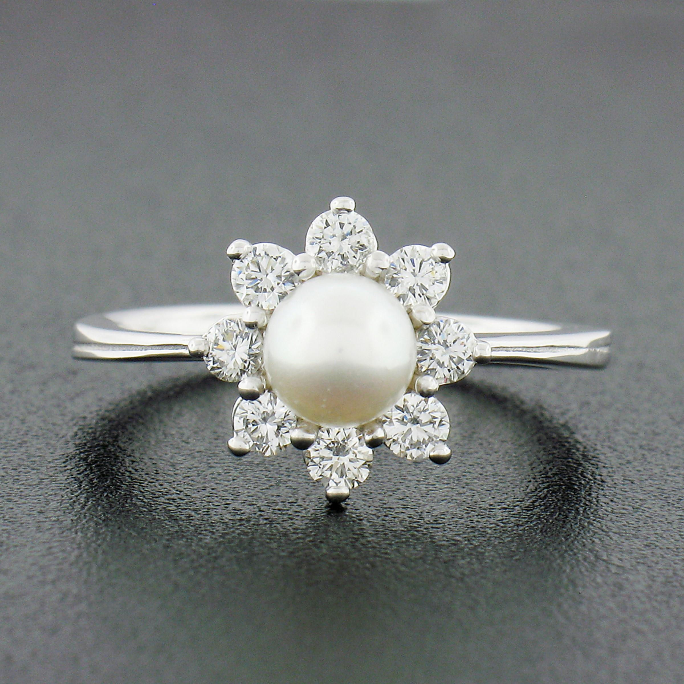 This classic pearl and diamond flower cluster ring is newly crafted in solid 18k white gold. It is neatly set at the center with a round cultured pearl that shows a nice white color with amazing luster. The pearl is further surround and accented by