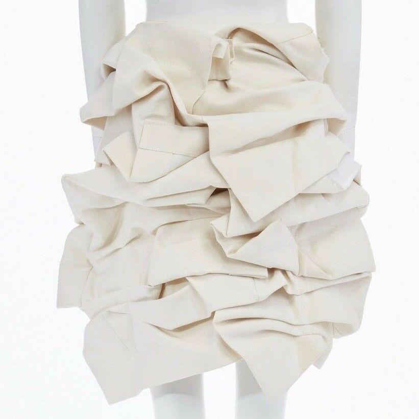 new COMME DES GARCONS Runway SS13 raw beige cotton bundled mini skirt S
COMME DES GARCONS BY REI KAWAKUBO
FROM THE SPRING SUMMER 2013 RUNWAY
Beige raw cotton . 
Bundled volume . 
Lightly padded . 
Raw seam details . 
Tonal stitching . 
Hook and eye