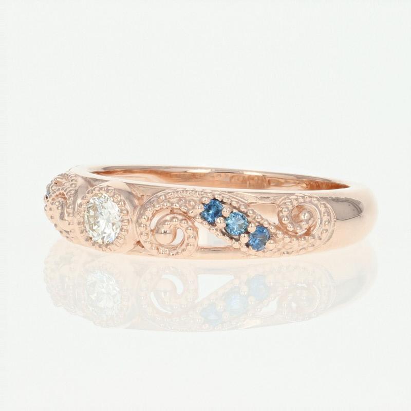 Romantically sweet and sophisticated, this NEW 14k rose gold band showcases a sparkling white diamond set between two milgrain-adorned flourishing scrolls which are kissed with shimmering blue sapphire accents. 

This ring is a size 6 1/2 - 6 3/4.