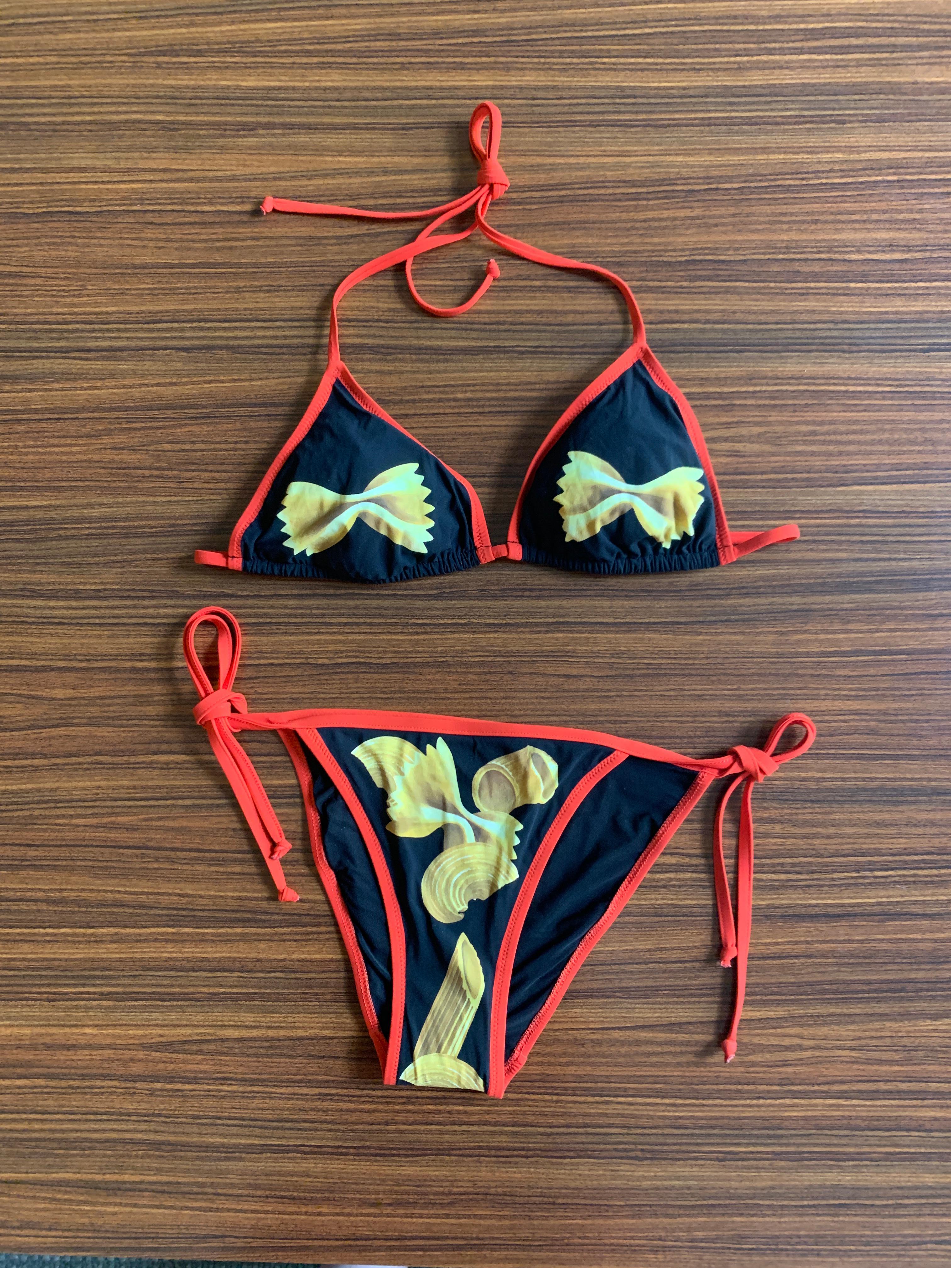Dolce & Gabbana black bikini featuring a variety of pasta. Yellow farfalle, macaroni noodles, and penne adorn this string bikini with red trim. 
A truly iconic print from Dolce & Gabbana's Spring/Summer 2017 collection.

75% polyamide, 25% elastane