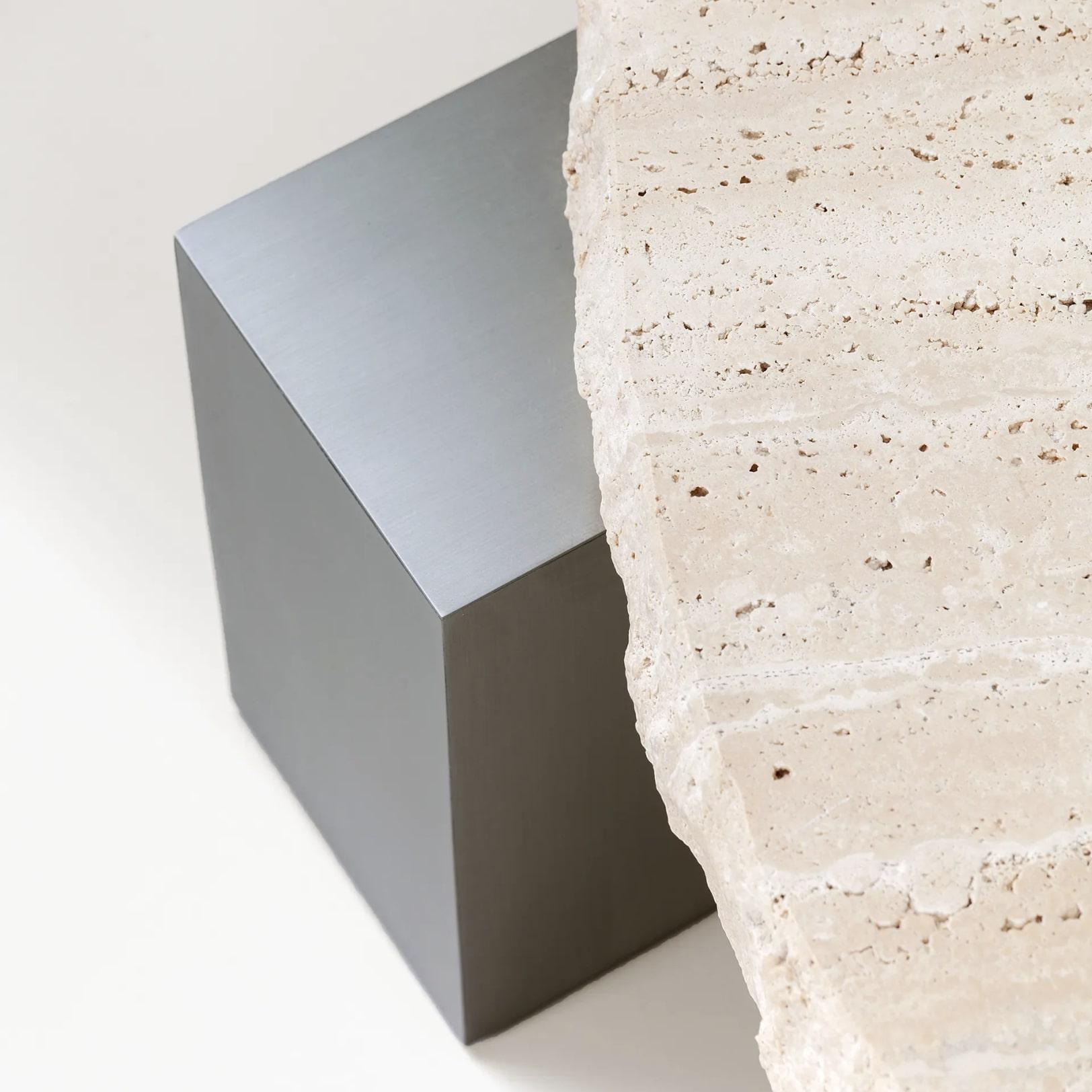 Exploration harmonieuse des contrastes, la table On the Rocks fait le lien entre l'organique et le futuriste. Avec un plateau en travertin martelé à la main qui exsude une beauté brute et naturelle et une base en nickel épurée qui reflète l'élégance