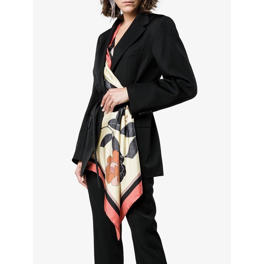 Elongated dry wool blazer with draped floral scarf detail protruding from interior.
Three-button closure
Notched lapels
Long sleeves with three-button cuffs.
Optional adjustable tonal fabric belt at waist.
Scarf detail may be buttoned at exterior or