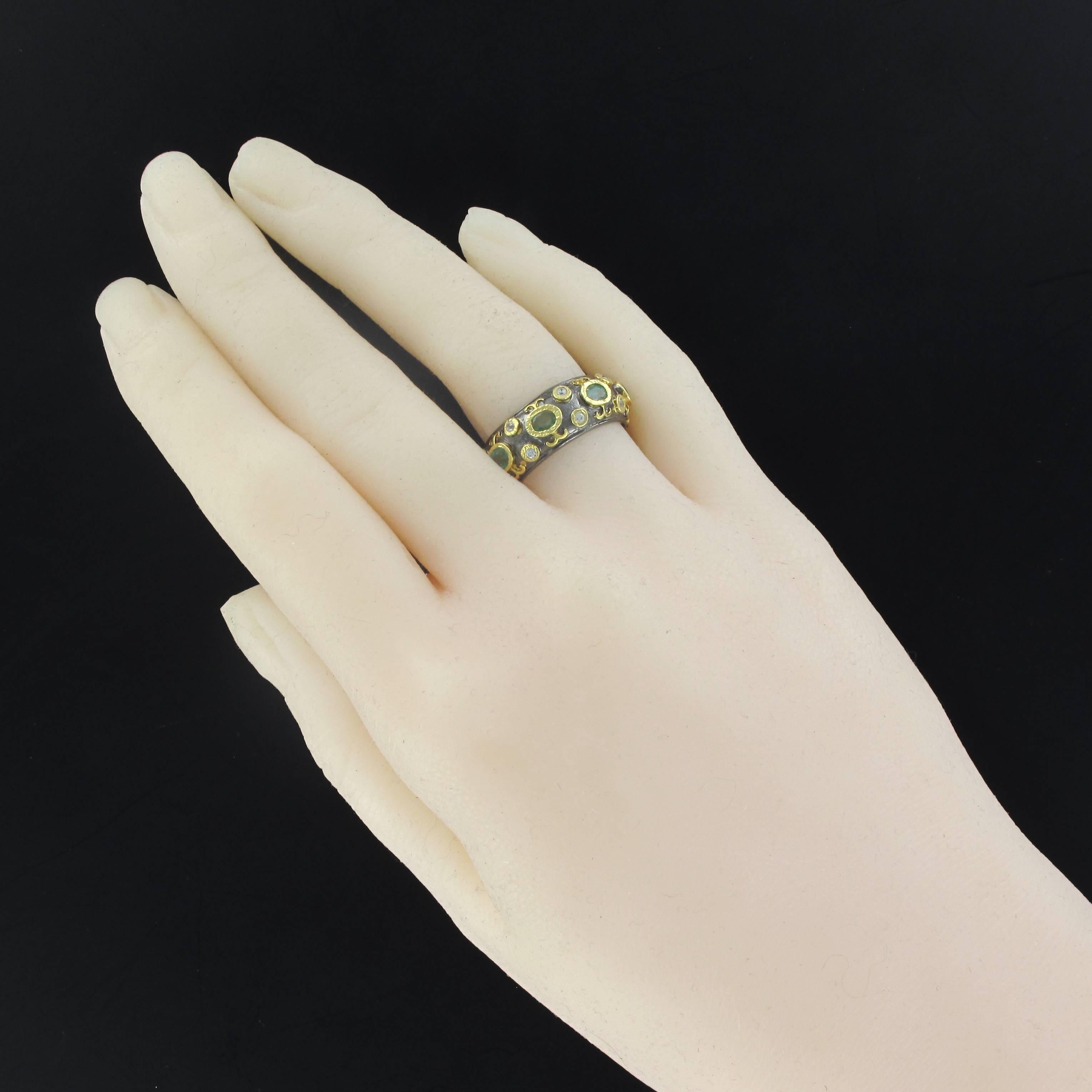 Ring in silver, 925 black rhodium-plated.
This rounded bangle ring is closed set on its top with an alternace of white topaz and emeralds, the whole set with a chiseled closed and rhodium plated yellow gold.
Total weight of emeralds: about 2.86