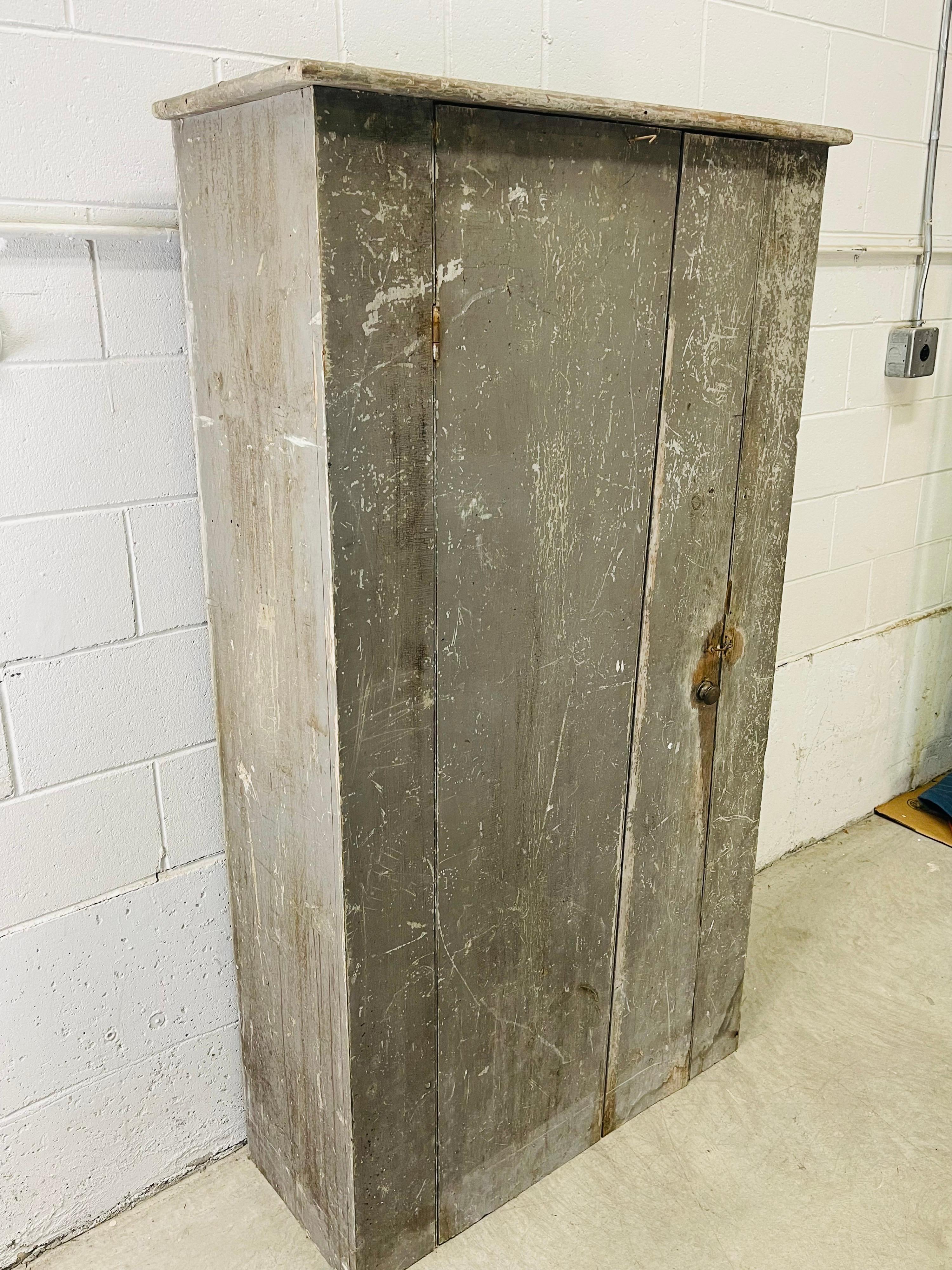New England farmhouse rustic antique wood cupboard in original condition. The cupboard has the original paint and hardware. There was never a back on the cupboard because it would have been built into a wall. There is only one hinge on the door