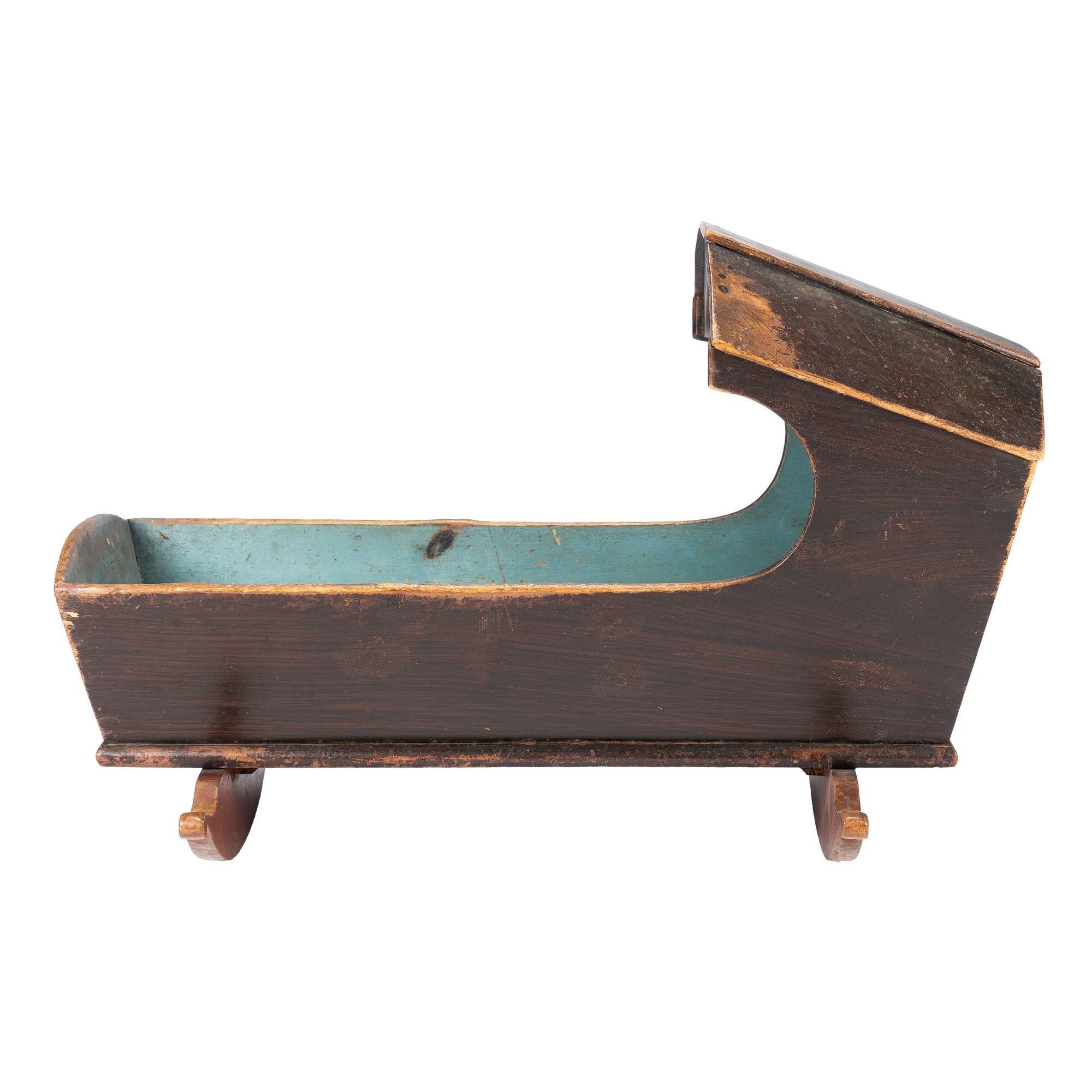 New England painted Northern white pine hooded rocking cradle. The cradle retains its original blue milk paint interior and grain painted exterior.
American, 1780-1810.