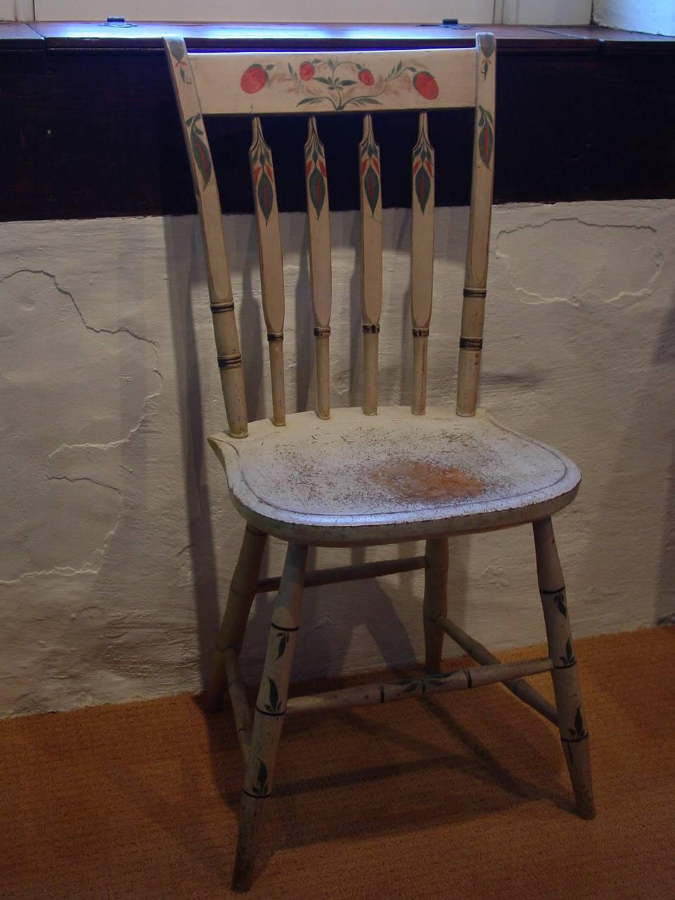 A white-painted slat-back Windsor side chair wonderfully decorated with a strawberry motif across the crest and foliate devices throughout. This Windsor chair likely originated in New York State or Northern New England, circa 1815, and would make a