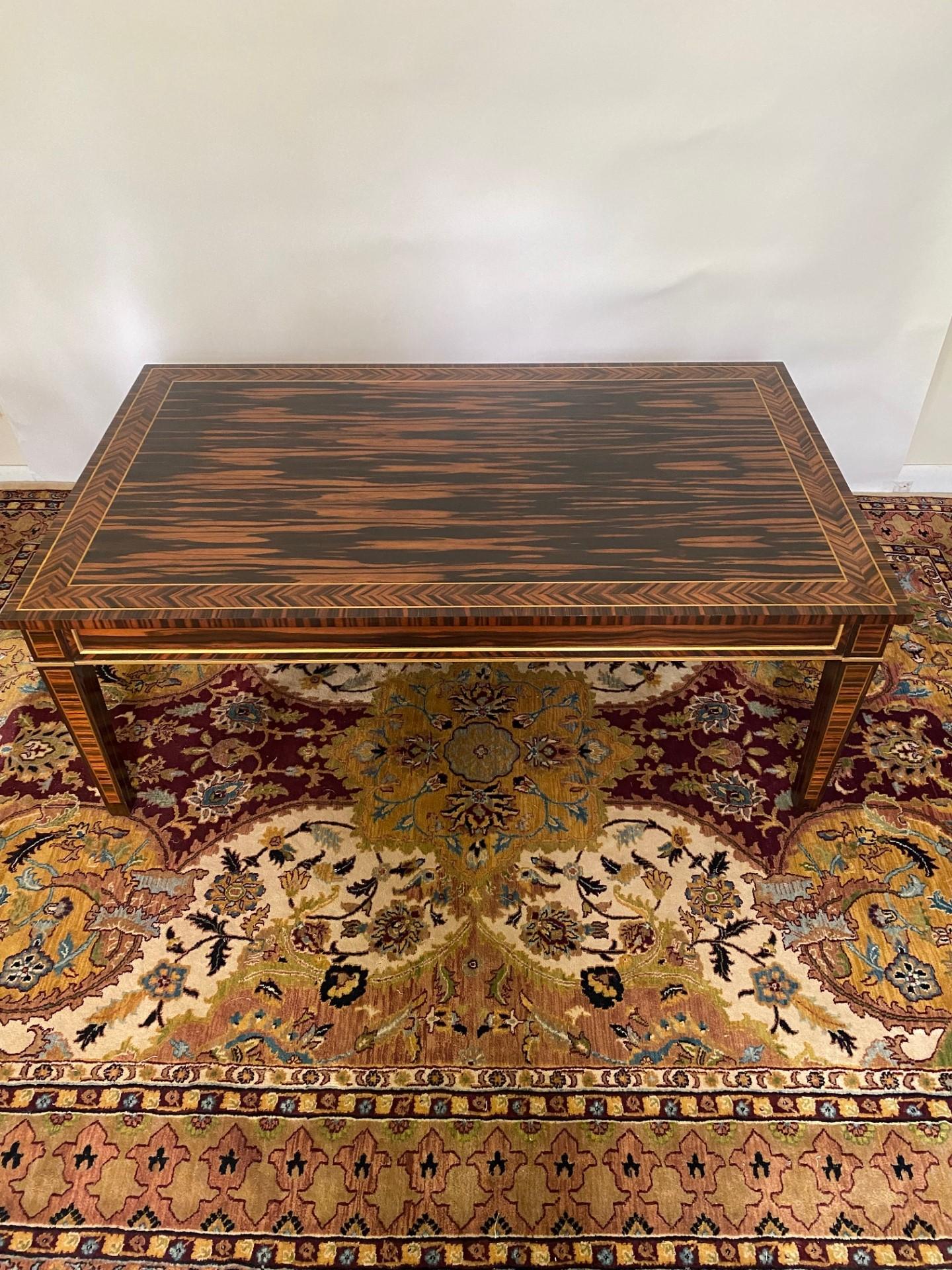 Cette table basse rectangulaire en coromandel de style Regency, fabriquée sur banc anglais par New Wood & HOGAN, est un meuble époustouflant qui respire l'élégance et la sophistication. Fabriquée avec le souci du détail, cette table basse met en