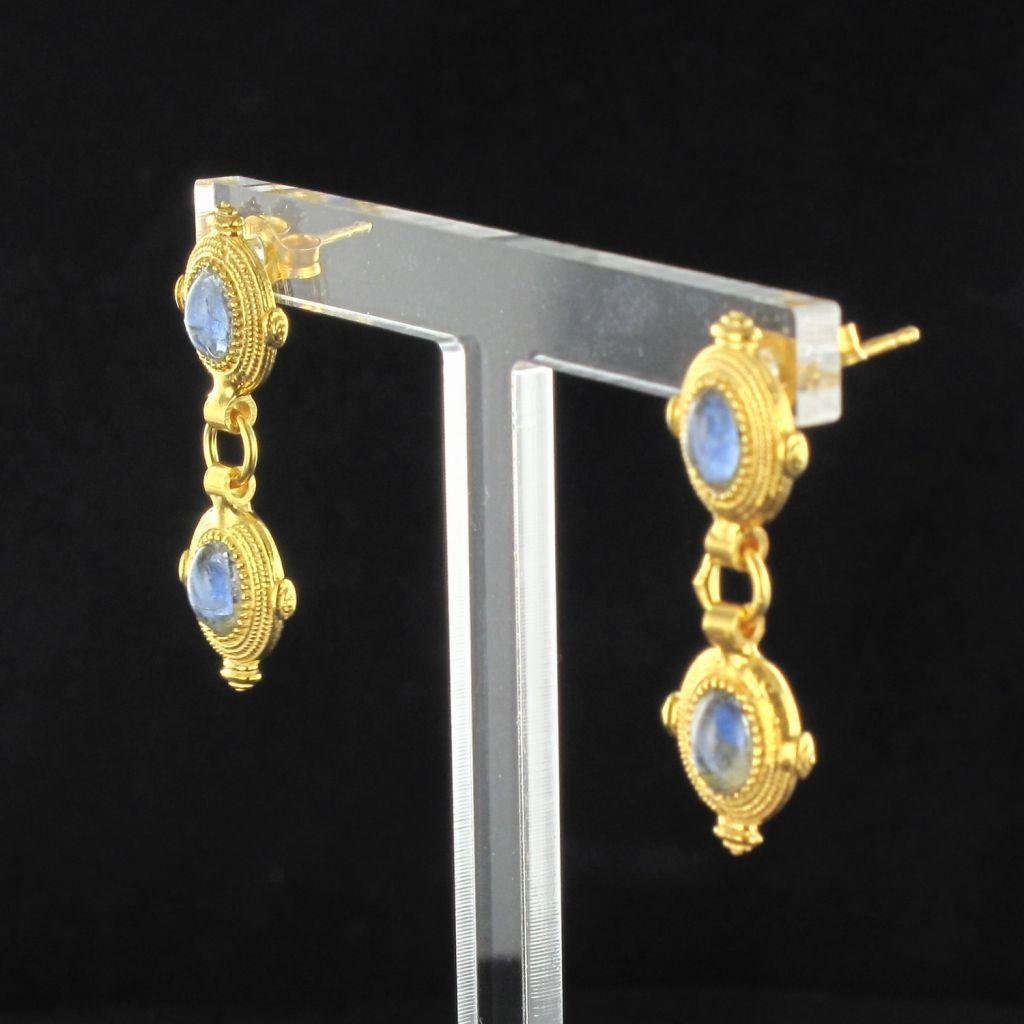 For pierced ears.
Pair of modern silver and yellow gold earrings.
Each vermeil earring is set with a cabochon stone on a chiseled pattern that supports a ring and the same pattern.
The hanging system of this designer jewelry is butterfly.
Length: