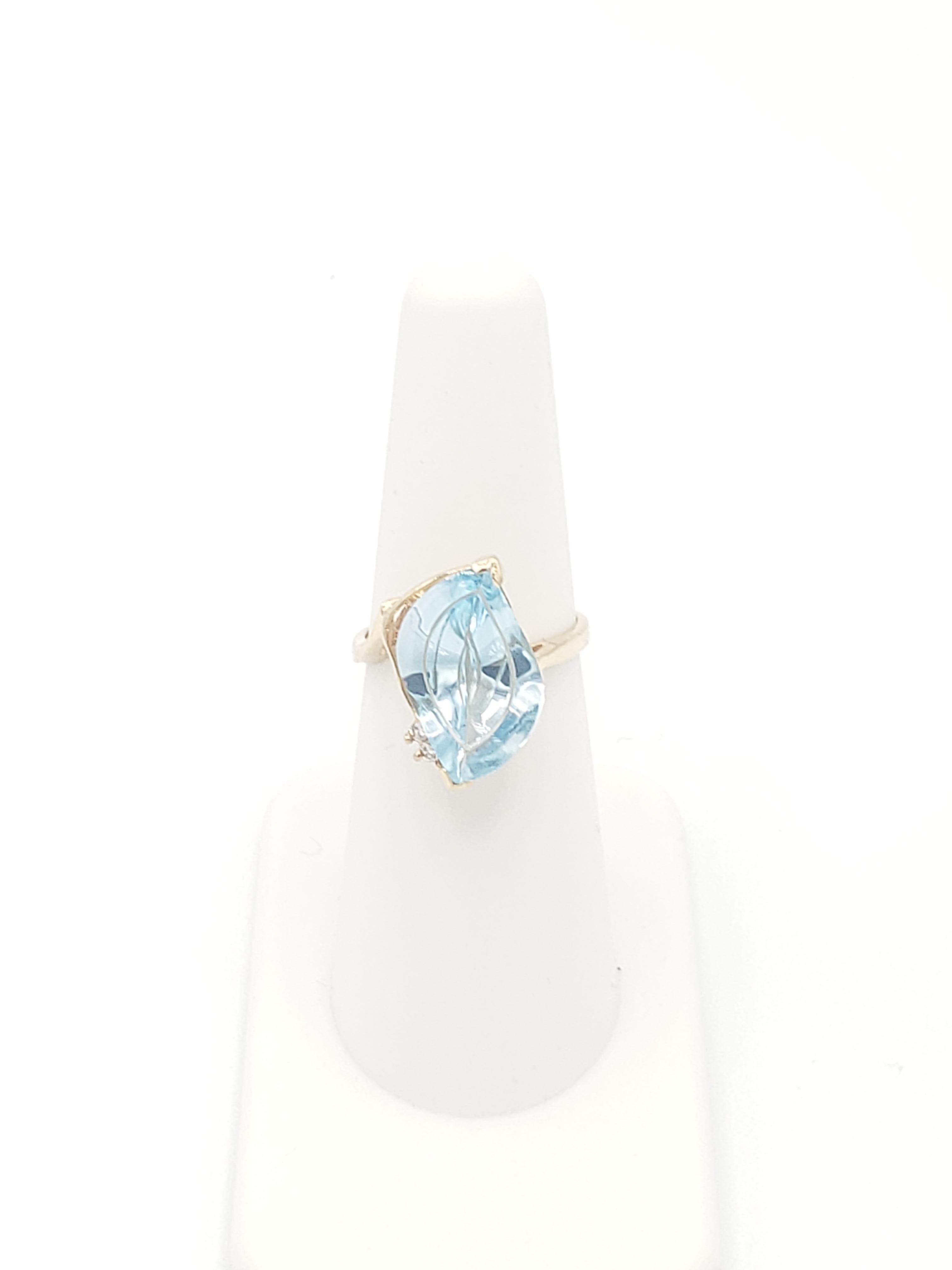 Cette magnifique bague Fantasy Cut présente une topaze bleue naturelle de 5 carats sertie dans un anneau en or jaune 14K massif. La bague est conçue dans un style couronne antique, avec des accents de diamants blancs et un poids total en carats de