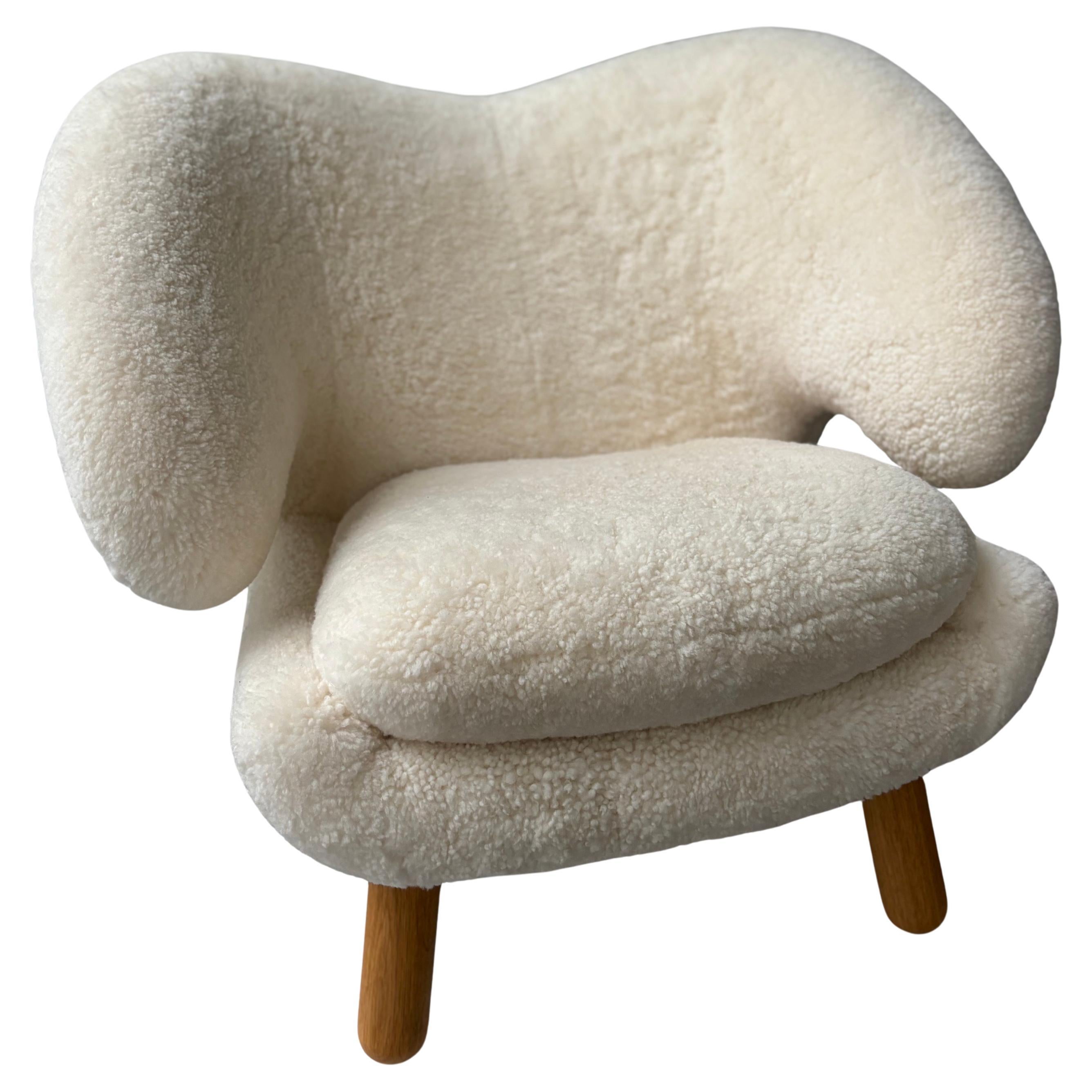 This is a like new original Pelican Chair in off-white Shearling with oak oil legs produced in Denmark by House of Finn Juhl in 2023. The chair has only been used as a floor sample in our Miami Scandinavian design showroom. The shearling has