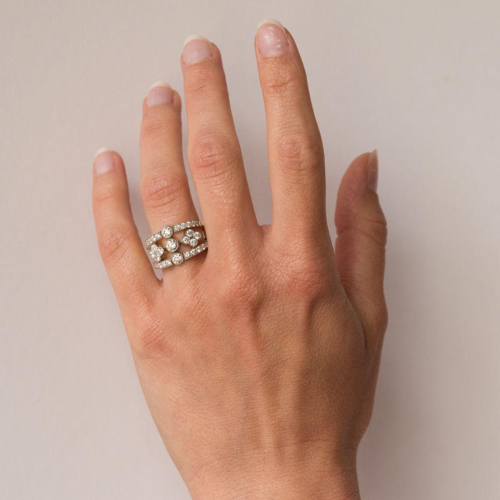 Ring aus 18 Karat Gelbgold, Adlerkopfpunze und Hundekopfpunze aus Platin.
In Form von zwei Bändern, die jeweils mit einem Diamanten in der Mitte und kleineren Diamanten in der Lünette besetzt sind, werden diese Bänder durch ein durchbrochenes Muster