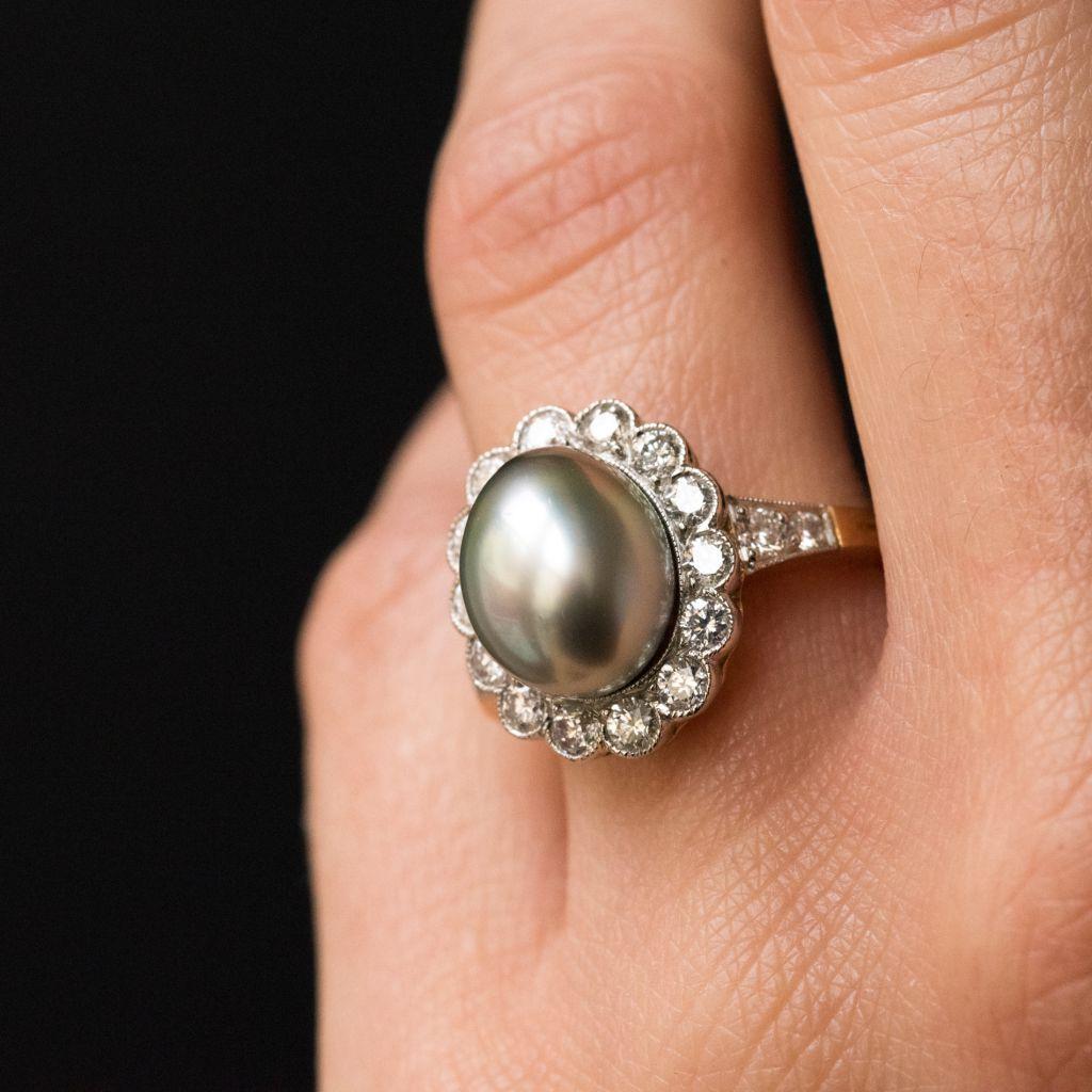 Ring in platinum and 18 karat yellow gold, eagle and dog heads hallmarks. 
Claw set with a tahitian grey natural pearl surrounded by 14 brilliant- cut diamonds in millegrain settings. At each side of this design on the beginning of the ring band are