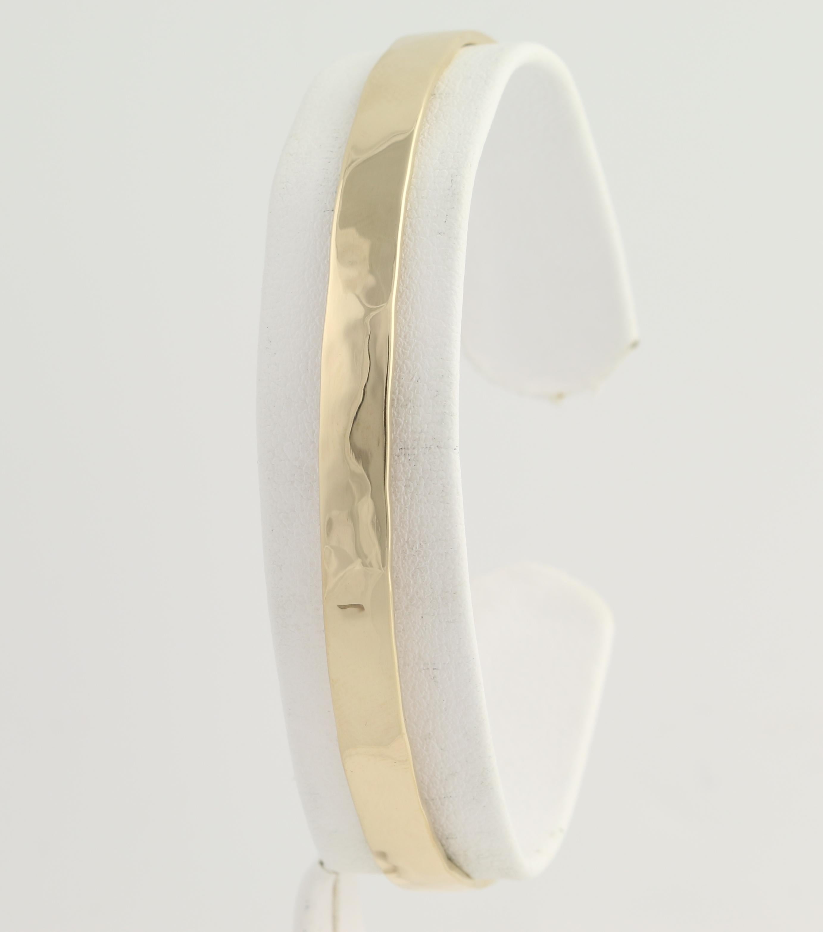 Treat yourself or a special friend to a chic, go-with-anything cuff bracelet! This brand-new piece is handmade from 14k yellow gold and the hammered face smoothly polished so that the cuff draws and reflects light with any movement. Solid in
