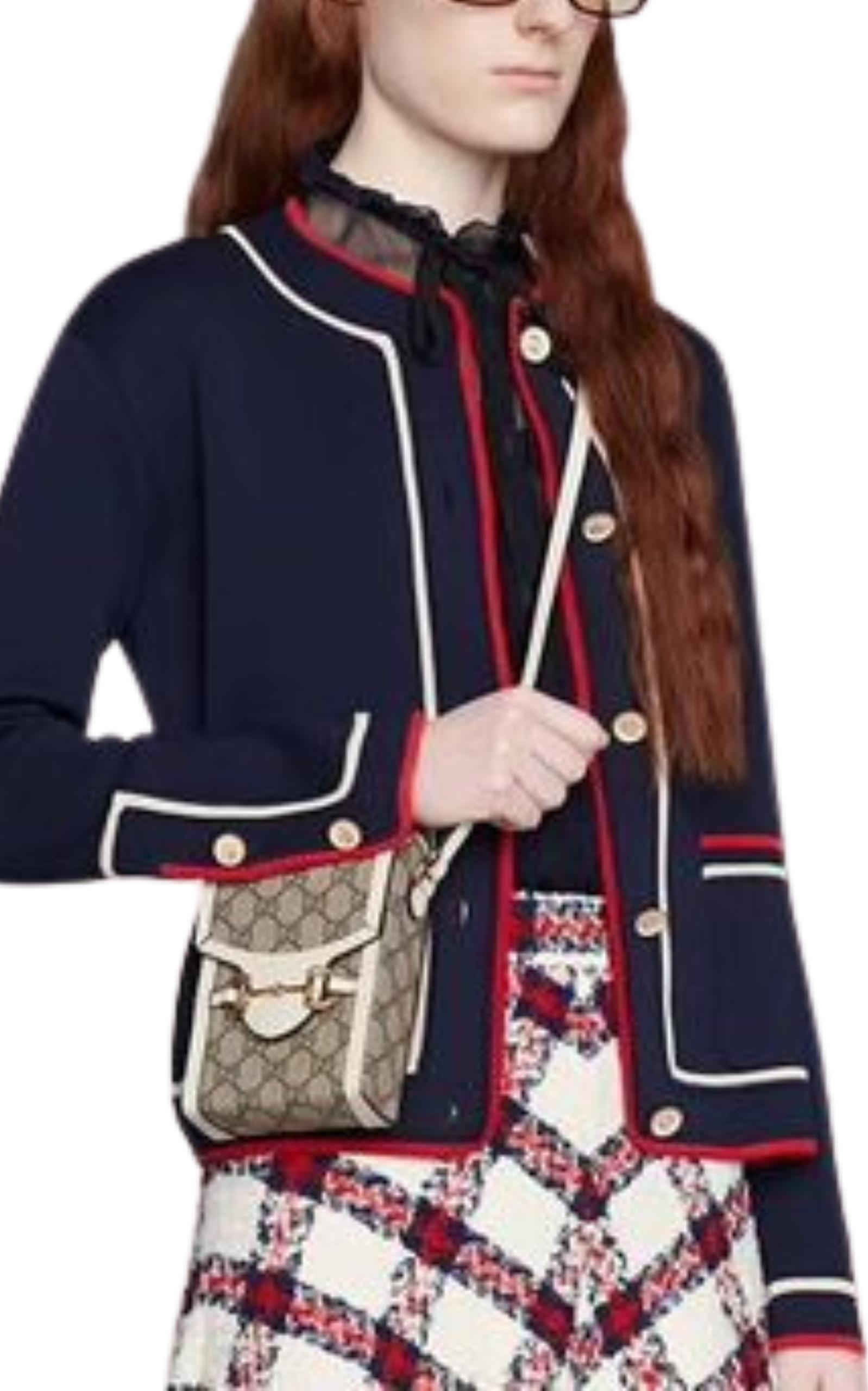 Ce mini sac Gucci Horsebit 1955 présente une combinaison de tissu GG Supreme beige et ébène avec des finitions en cuir blanc et des détails dorés. La fermeture en mors de cheval est assurée par un bouton automatique. 
Il est réalisé à partir d'une