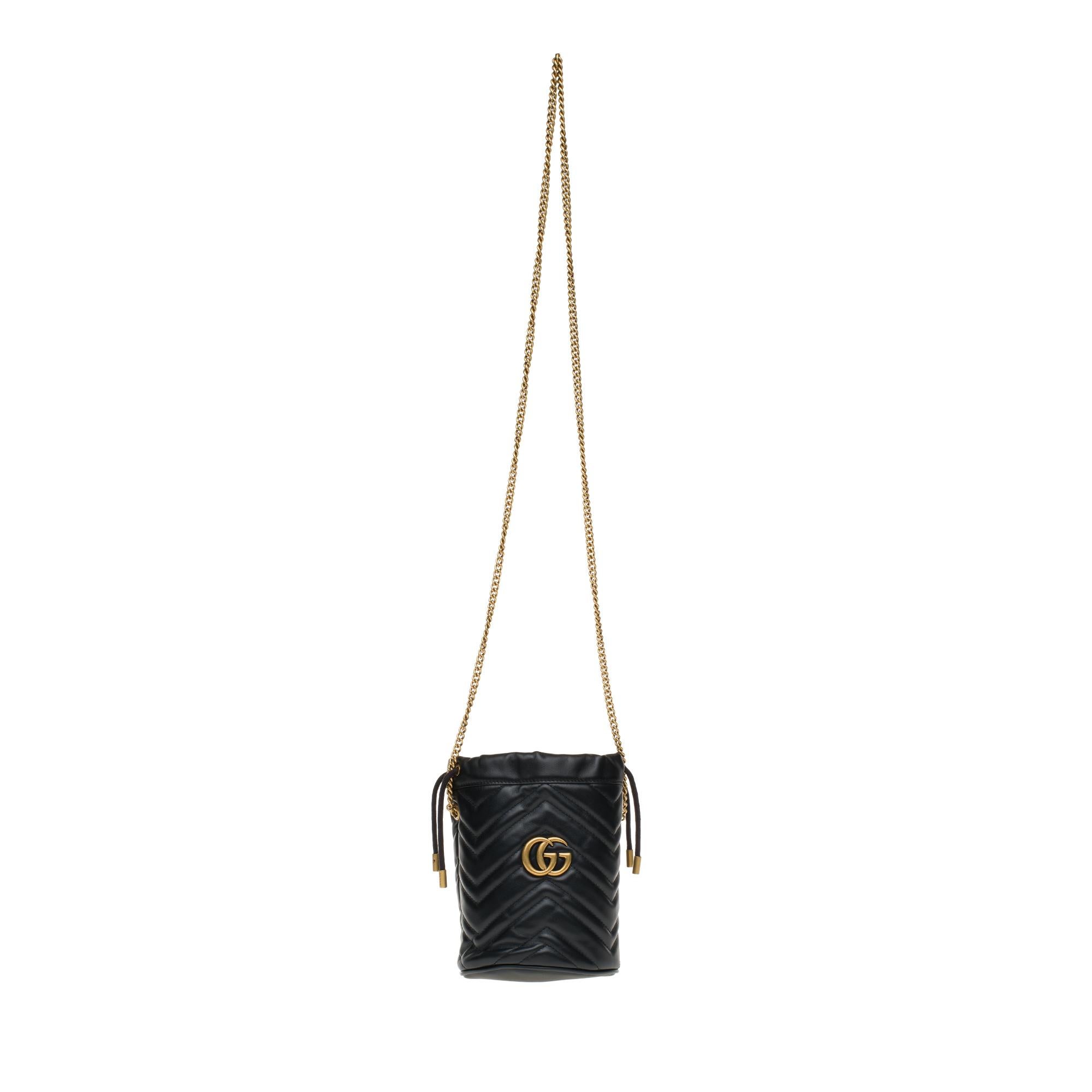 Gucci mini bucket bag GG Marmont made in black quilted leather with chevrons. Inspired by a model from the archives of the 70’s, a flagship period for the House, the Double G adorns the front of this accessory. With its chain shoulder strap and