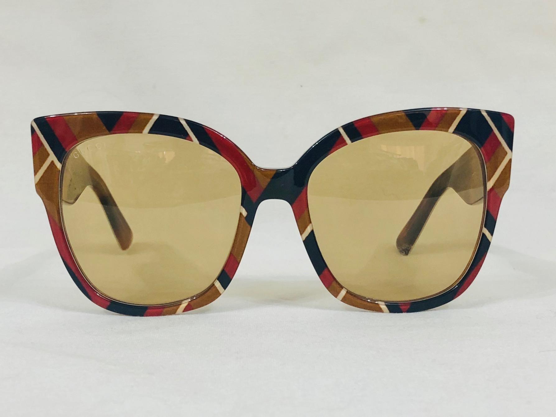 An instant classic, these new Gucci Sunglasses feature a square, cat eye and signature studs on the temples.  Light amber tint lenses and warm multi-color print frames complement any fall look.  Hard to find in new condition with hard case,