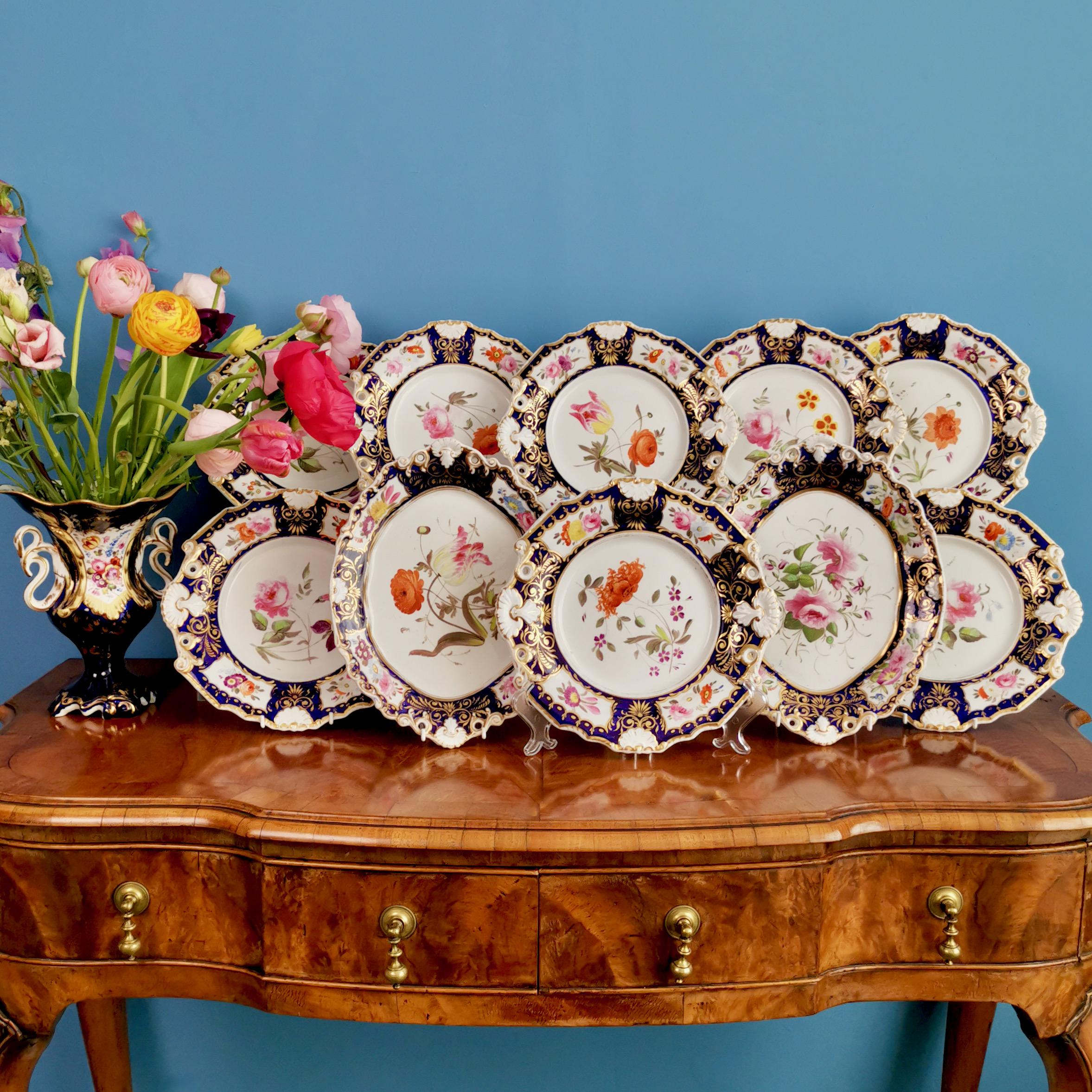 This is a very striking and rare part dessert service made by New Hall between 1824 and 1830. The service consists of 8 plates and 2 oval serving dishes, and is decorated in cobalt blue, gilt and stunning flower paintings in the central reserve and