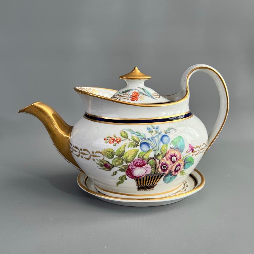 This is a very elegant tea service made by New Hall around the year 1810. The service is made of hybrid hard-paste porcelain and has beautiful hand painted flower baskets set in a mazarine blue and gilt border. The service consists of a teapot with