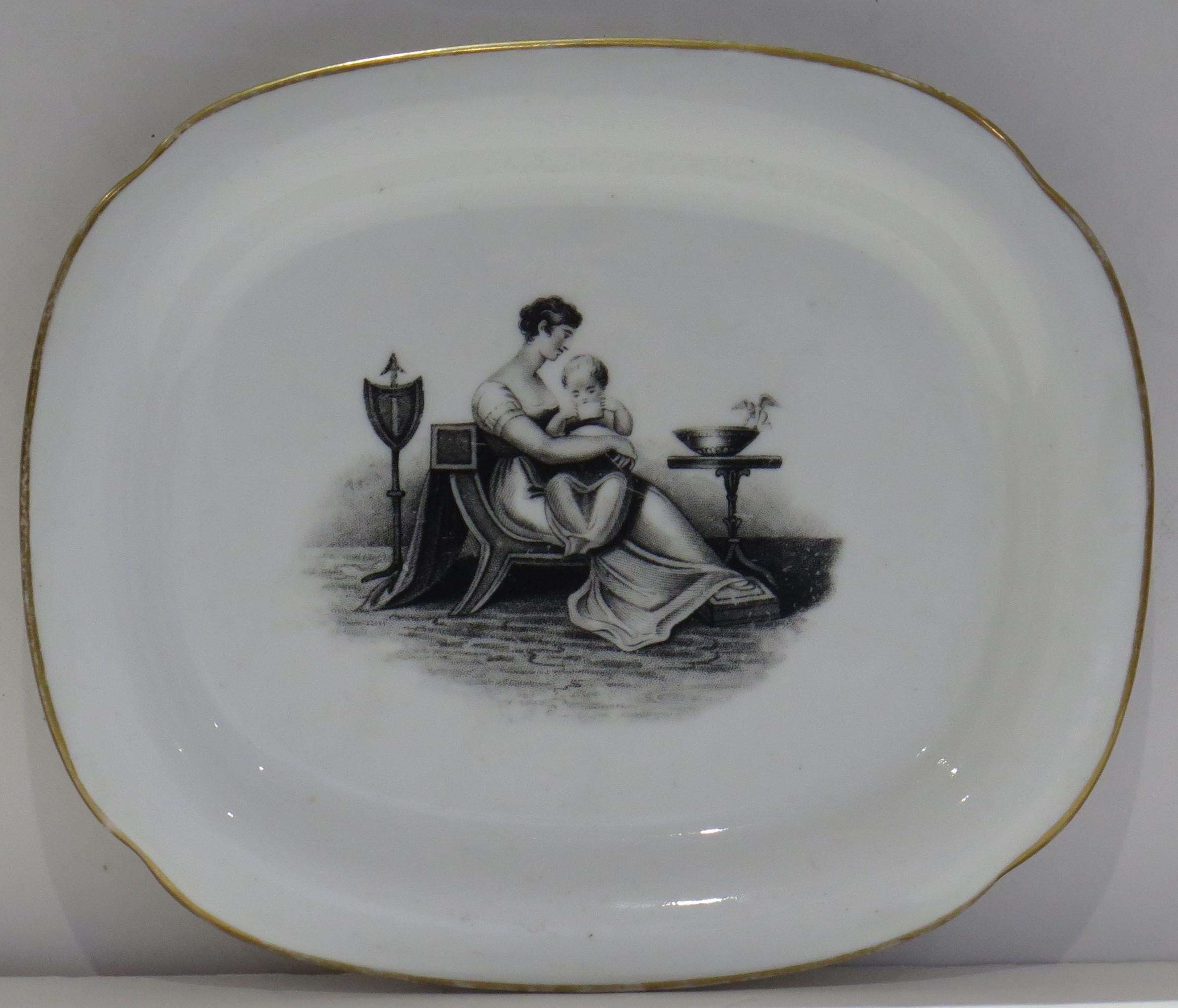 This is a bone china porcelain Dish or Stand by New Hall dating to the Georgian Regency period of the early 19th century, circa 1820.

The dish is well potted on a low foot. 

The decoration is bat printed in the manner of Adam Buck, with a