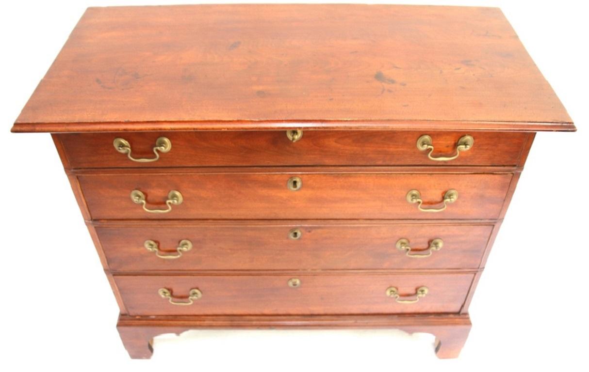 Chippendale four-drawer chest in birch with slight figuring. The case features a bold rectangular over-hanging top above four dovetailed and graduated long drawers fitted with brass bail handles resting on a molded base ending in tall bracket