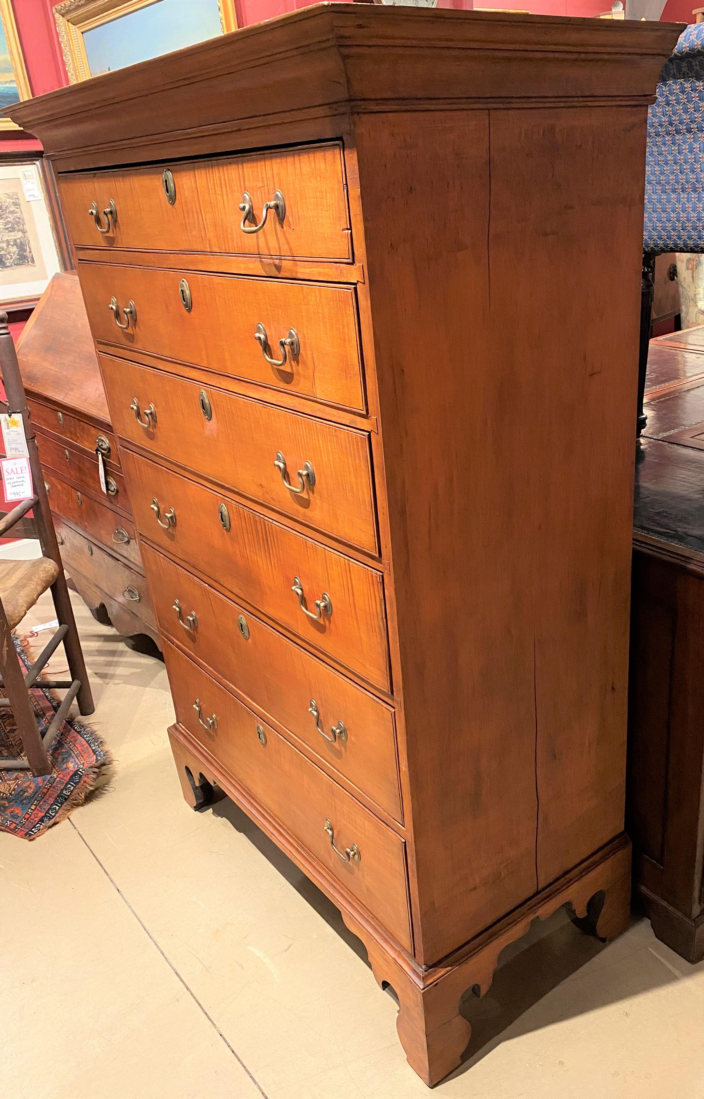 A fine tiger maple tall chest with molded cornice surmounting six graduated long drawers with period replaced brasses, with locks removed, dovetailed construction, and original wide back boards, all supported by a nicely carved bracket base.