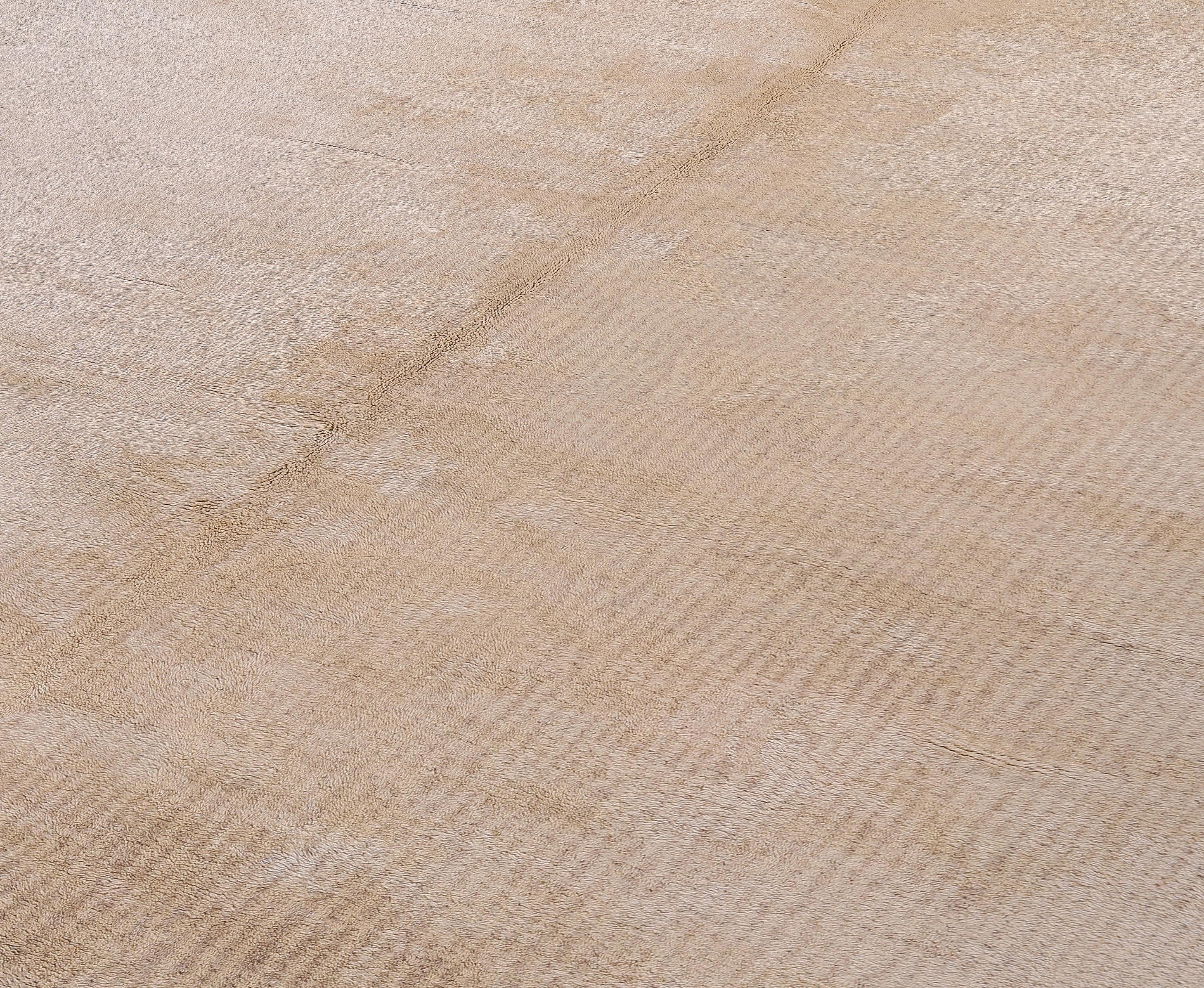 Experience refined Moroccan craftsmanship with this newly made hand-knotted rug in a soothing beige palette. Inspired by traditional Moroccan weaving, this contemporary piece blends minimalist design with luxurious texture. The subtle geometric