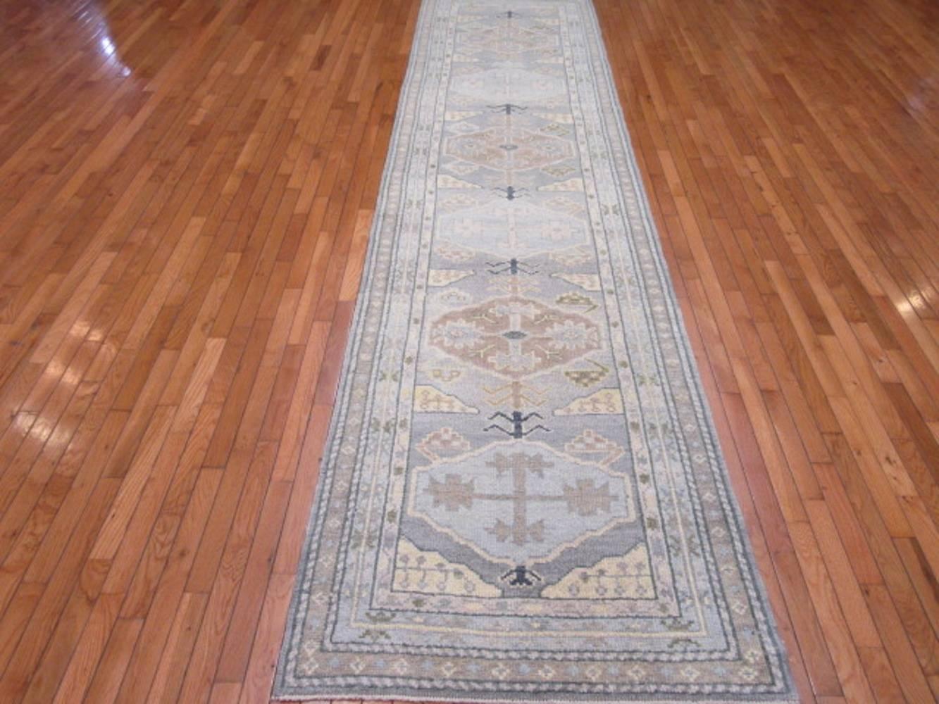 This is a new hand-knotted Turkish Oushak runner rug. It is made with 100% wool colored with natural dyes in contemporary popular tones. It's durable construction make it a great fit for any hall or space in the house. It measures 3' 3'' x 13' 1''.