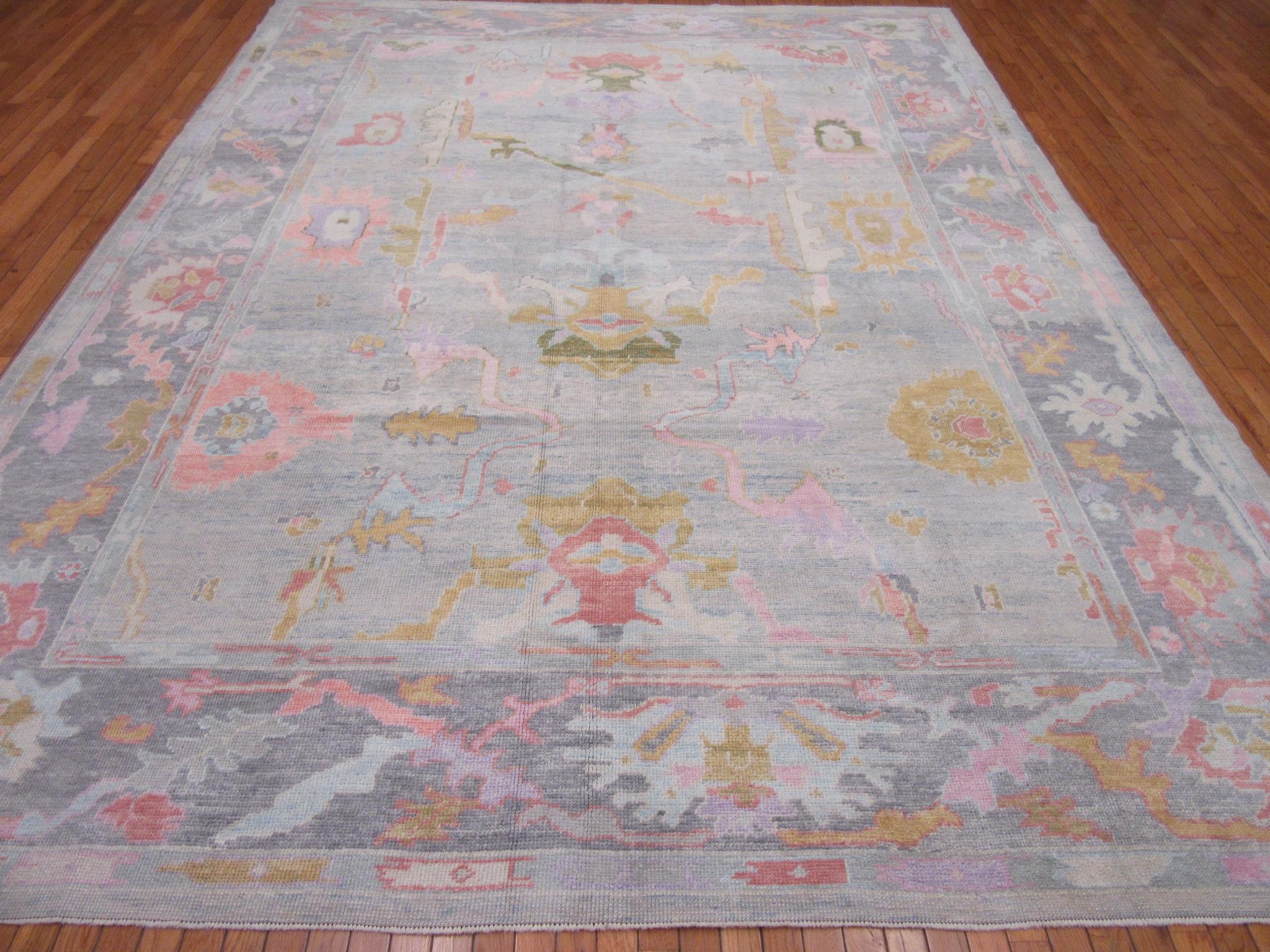 This is a new hand knotted room size Oushak design rug from Turkey. It is made with wool pile and wool foundation in a low pile finish and dyed with multiple fresh colors. It is a fun and happy rug with endless possibilities. It measures 9' x 12'.