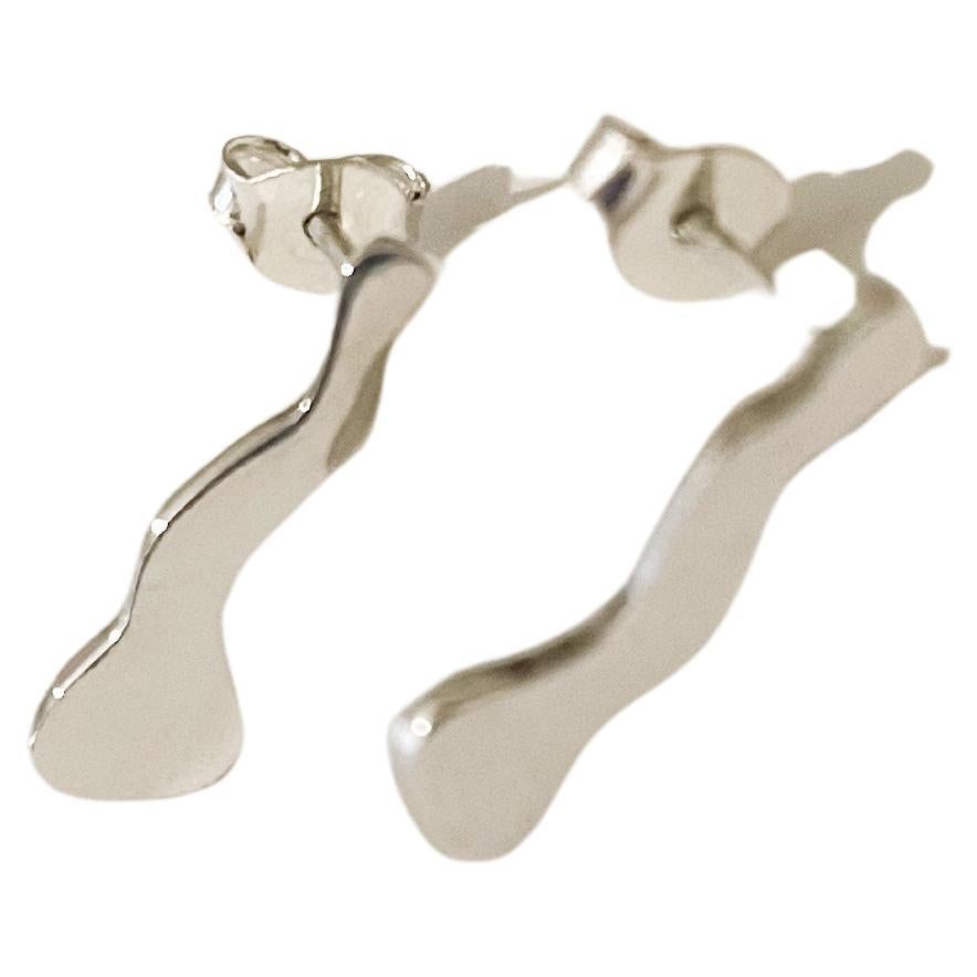 These small handcrafted earrings in 925 sterling silver showcase a playful, irregular shape that balances asymmetry and elegance. Measuring approximately 4 mm at their widest point, 2 mm at their narrowest, and 1.6 cm in length, they offer a subtle