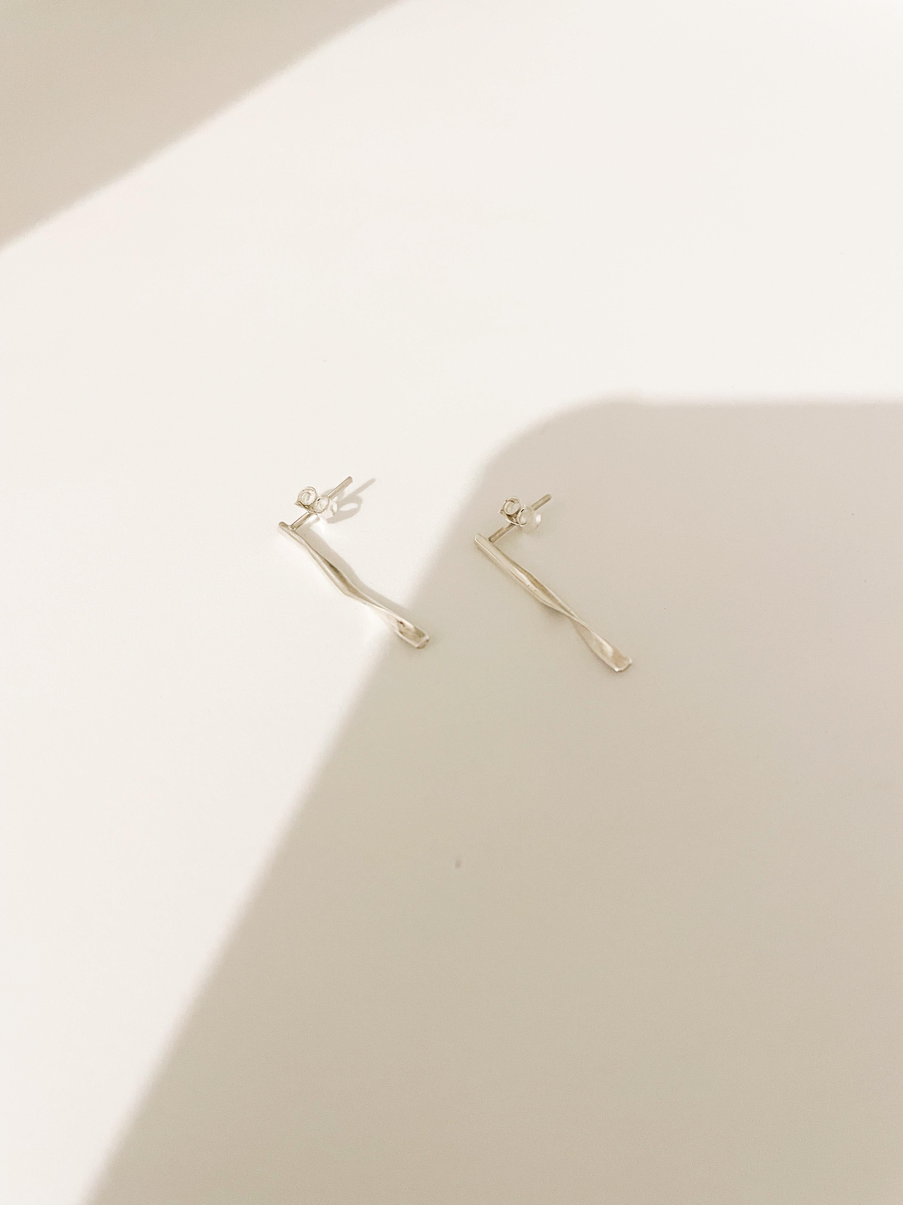 These handcrafted 925 sterling silver earrings are a study in delicate elegance and minimalism. Shaped like a small twisted stick, each earring measures approximately 2 mm in width and 2,5 cm in length. The subtle spiral form captures light and