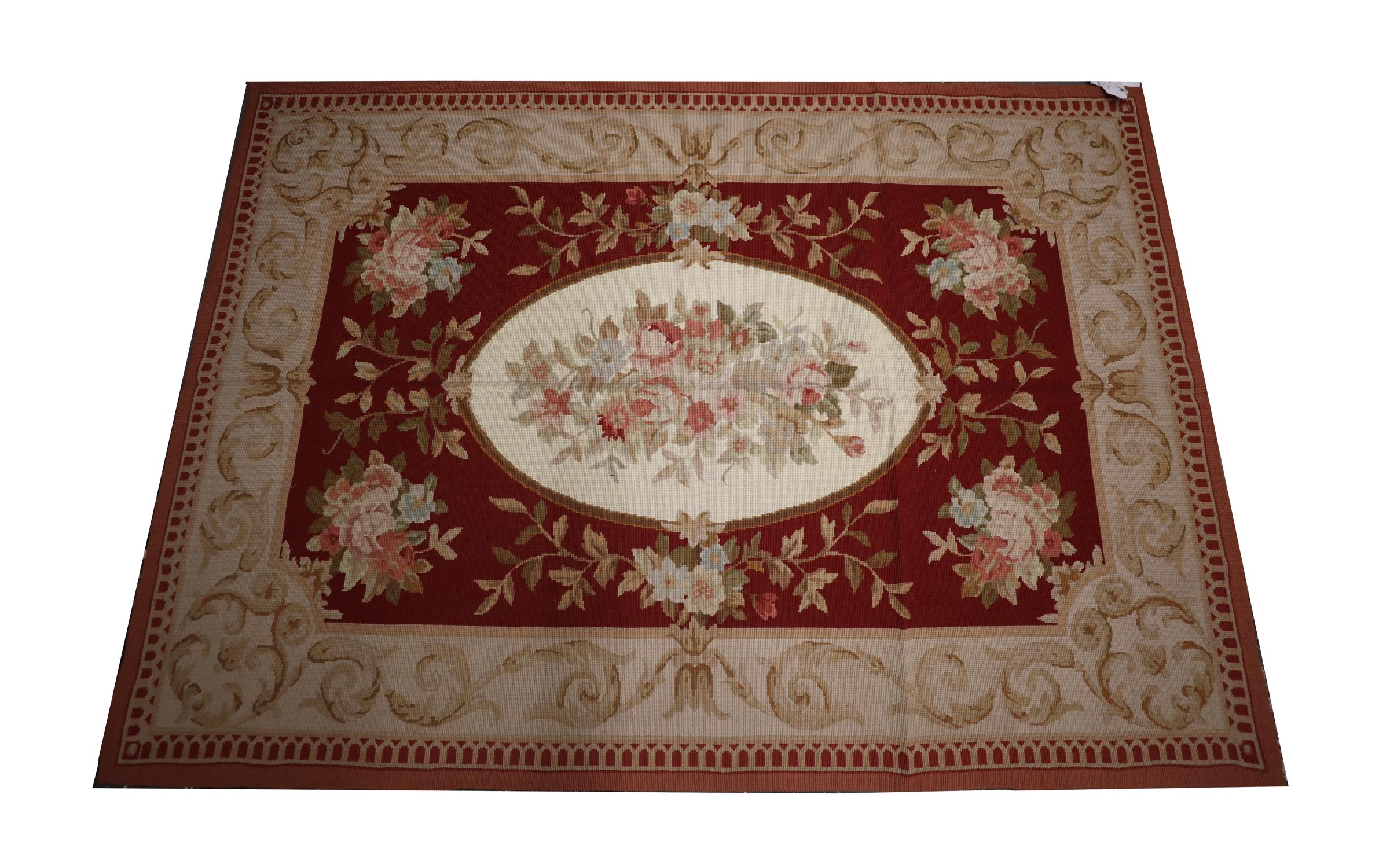 This New English style needlepoint was handwoven in the early 21st century and features a traditional Aubusson design with an oval central medallion and symmetrical surrounding design. Woven with an elegant colour palette of deep red, beige and