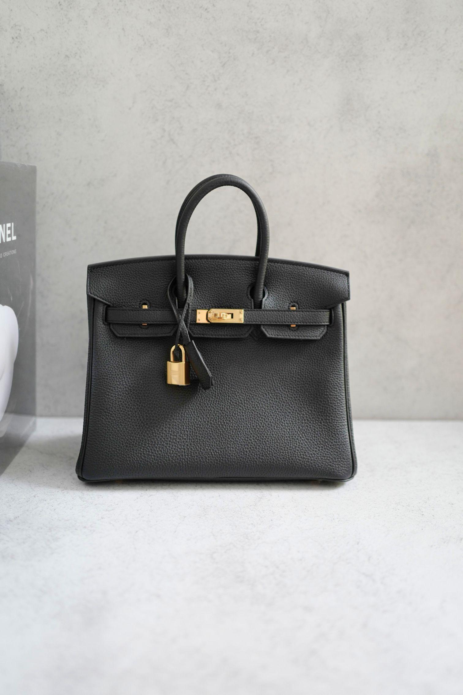La Birkin 25 di Hermès in Togo Noir con finiture in oro è un'icona di eleganza senza tempo e lusso raffinato. Realizzato in pregiata pelle di Togo, questo pezzo è famoso per la sua texture a grana fine, la sua resistenza e la sua sofisticata