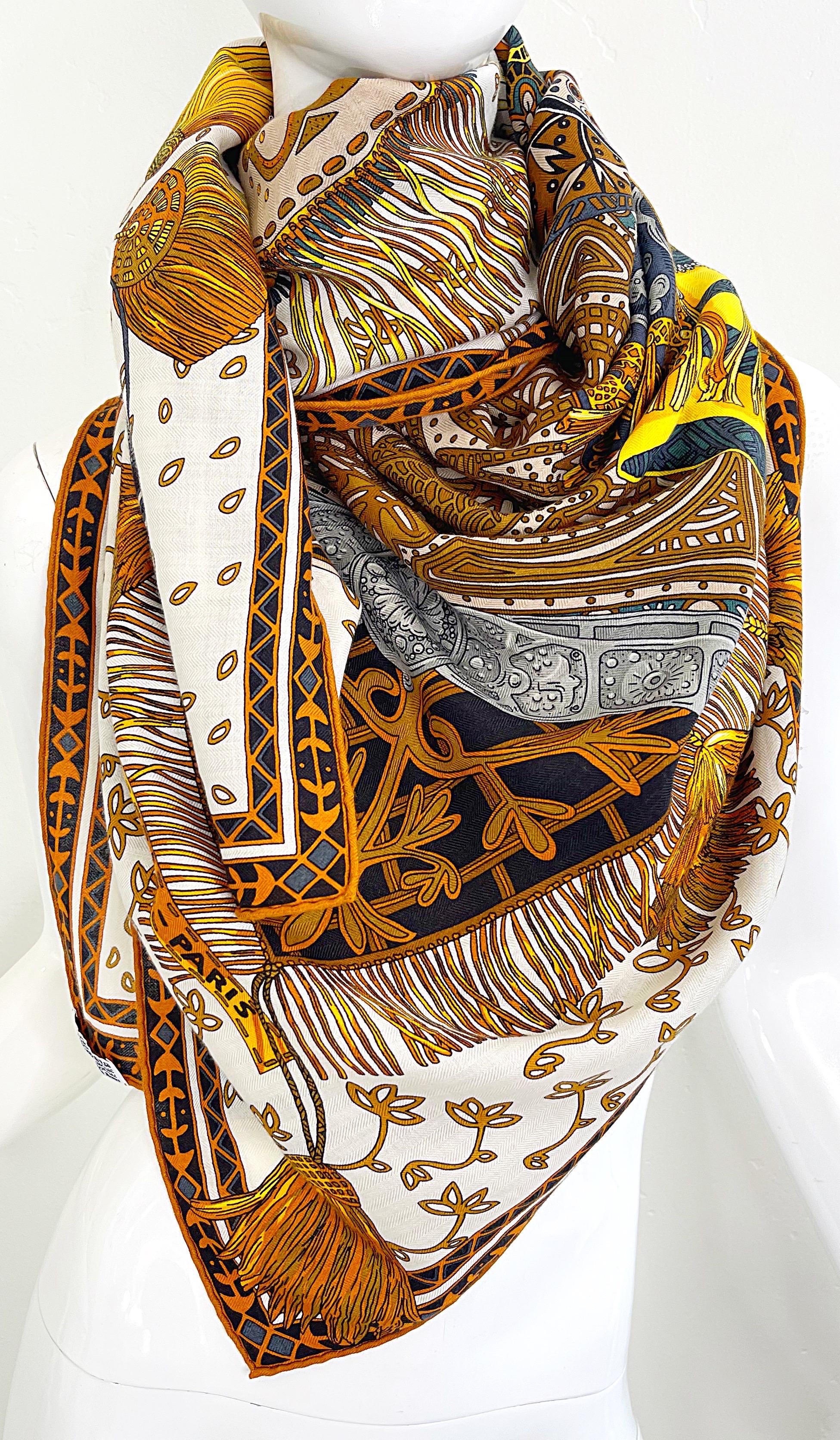 Brand new Hermes ‘Cavaliers du Caucase’ huge cashmere (65%) and silk (35%) shawl. Warm colors of blue, teal, turquoise, gold, orange, gray, yellow and white throughout. 
This intricate design by Annie Faivre is a richly detailed tribute to the