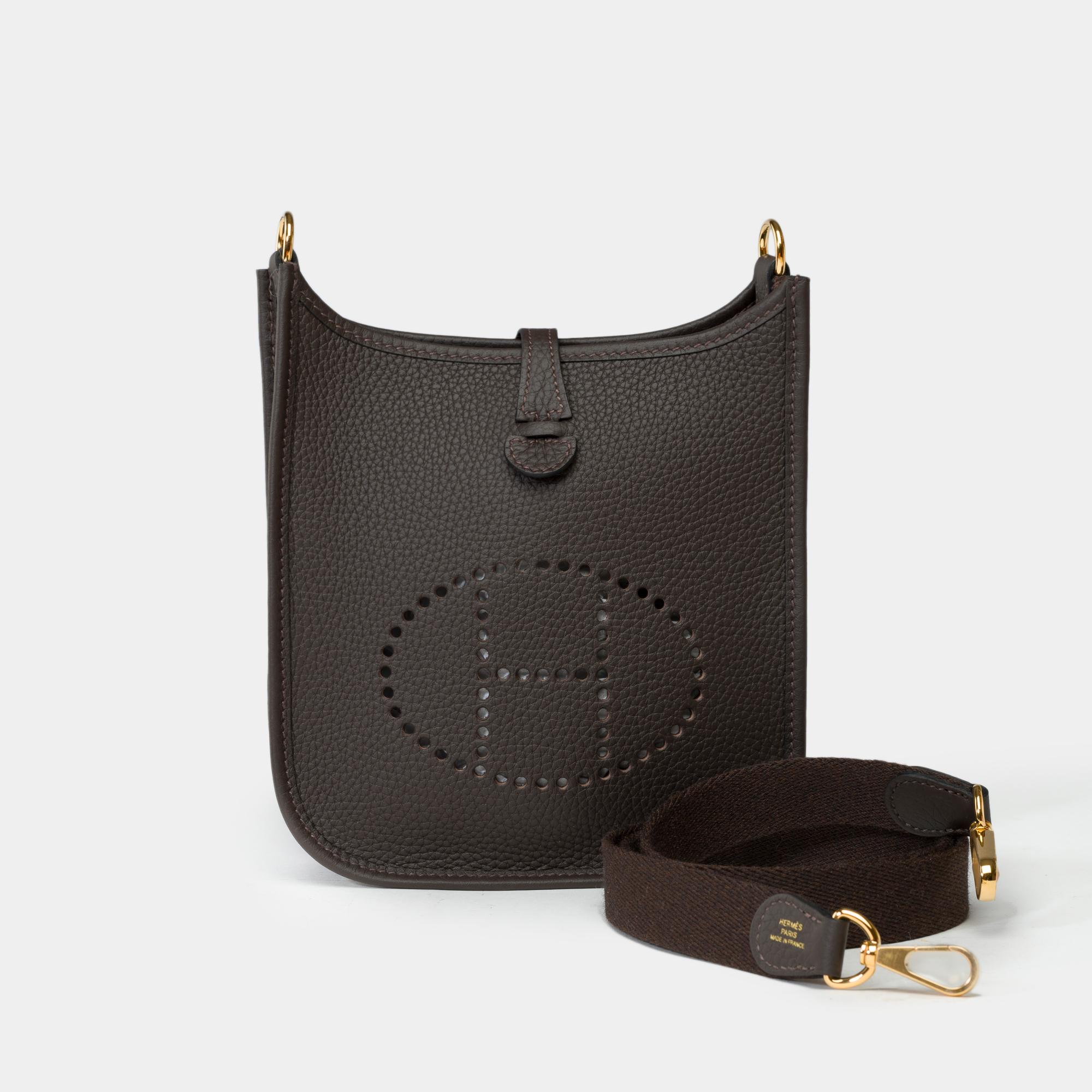 Splendid​ ​Hermes​ ​Evelyne​ ​16​ ​TPM​ ​shoulder​ ​bag​ ​in​ ​ebony​ ​(brown)​ ​Togo​ ​leather,​ ​gold-tone​ ​metal​ ​trim​ ​,​ ​a​ ​removable​ ​shoulder​ ​strap​ ​in​ ​brown​ ​canvas​ ​allowing​ ​a​ ​shoulder​ ​or​ ​crossbody

Press-stud​