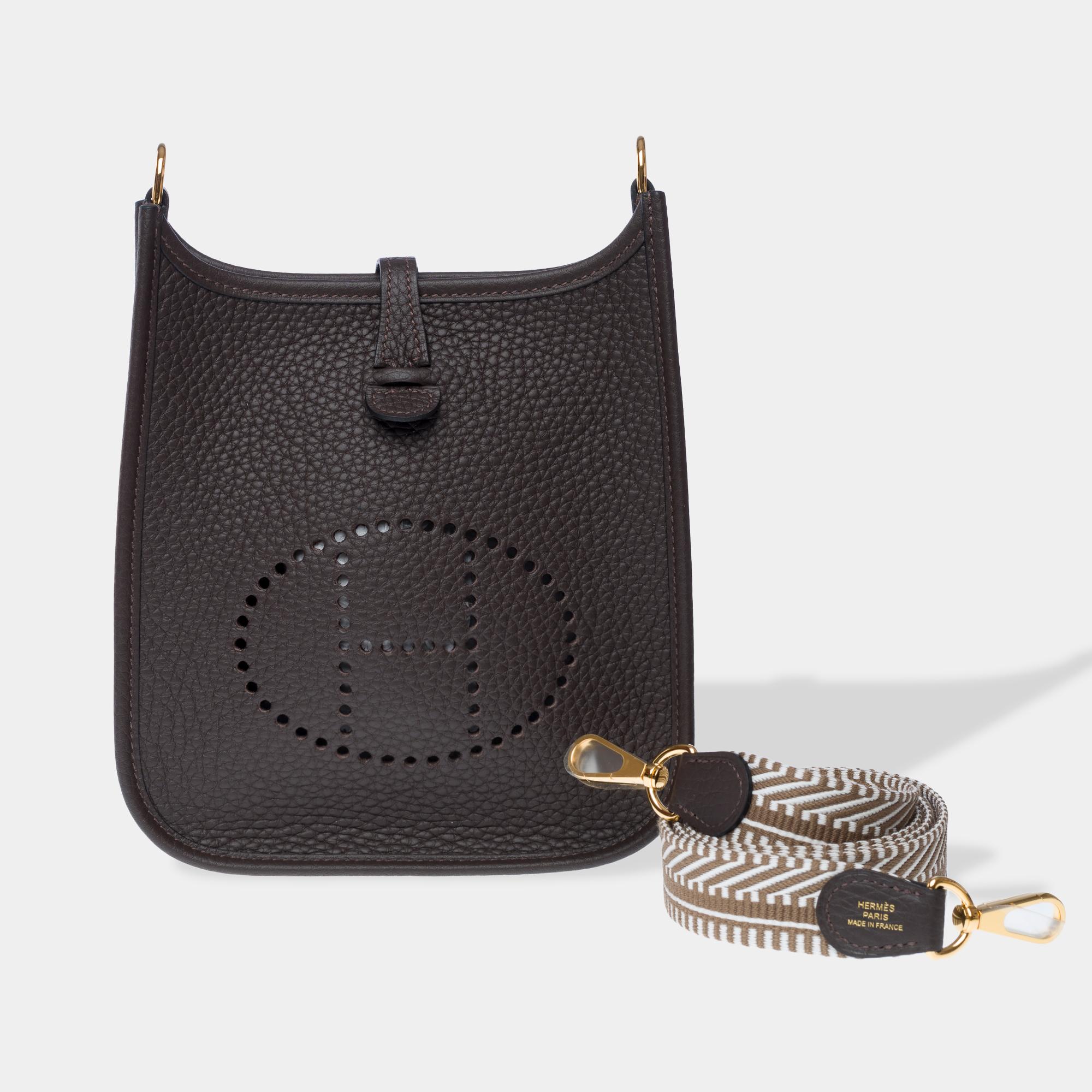 Splendid​ ​Hermes​ ​Evelyne​ ​16​ ​TPM​ ​Amazone​ ​shoulder​ ​bag​ ​in​ ​ebony​ ​brown​ ​Taurillon​ ​Clemence​ ​calfskin​ ​leather,​ ​with​ ​gold​ ​metal​ ​hardware,​ ​a​ ​removable​ ​shoulder​ ​strap​ ​handle,​ ​and​ ​Cavale​ ​bicolored​ ​ebony​