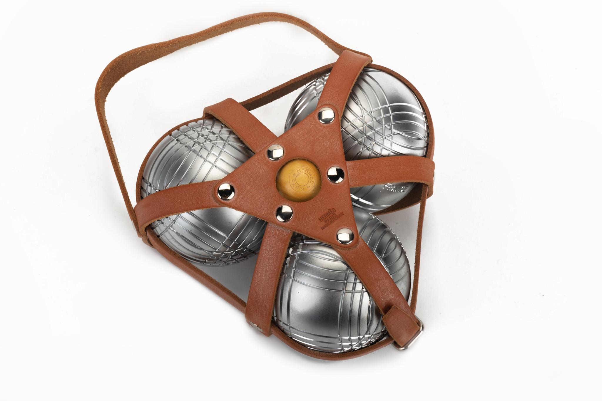 Jeu de boules de pétanque Hermès tout neuf. Publié en 2013:: cet ensemble de pétanque est livré avec trois boules en métal satiné:: une petite boule en bois (cochonnet) et un support en cuir brun naturel. Livré avec la housse de protection d'origine