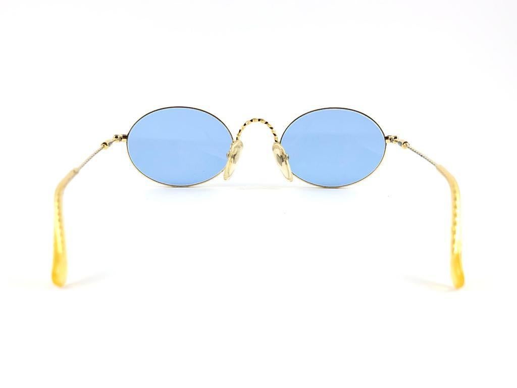 New Jean Paul Gaultier small oval gold frame.
Spotless light blue lenses that complete a ready to wear JPG look.

Amazing design with strong yet intricate details.
Design and produced in the 1990's.
New, never worn or displayed. This item may show