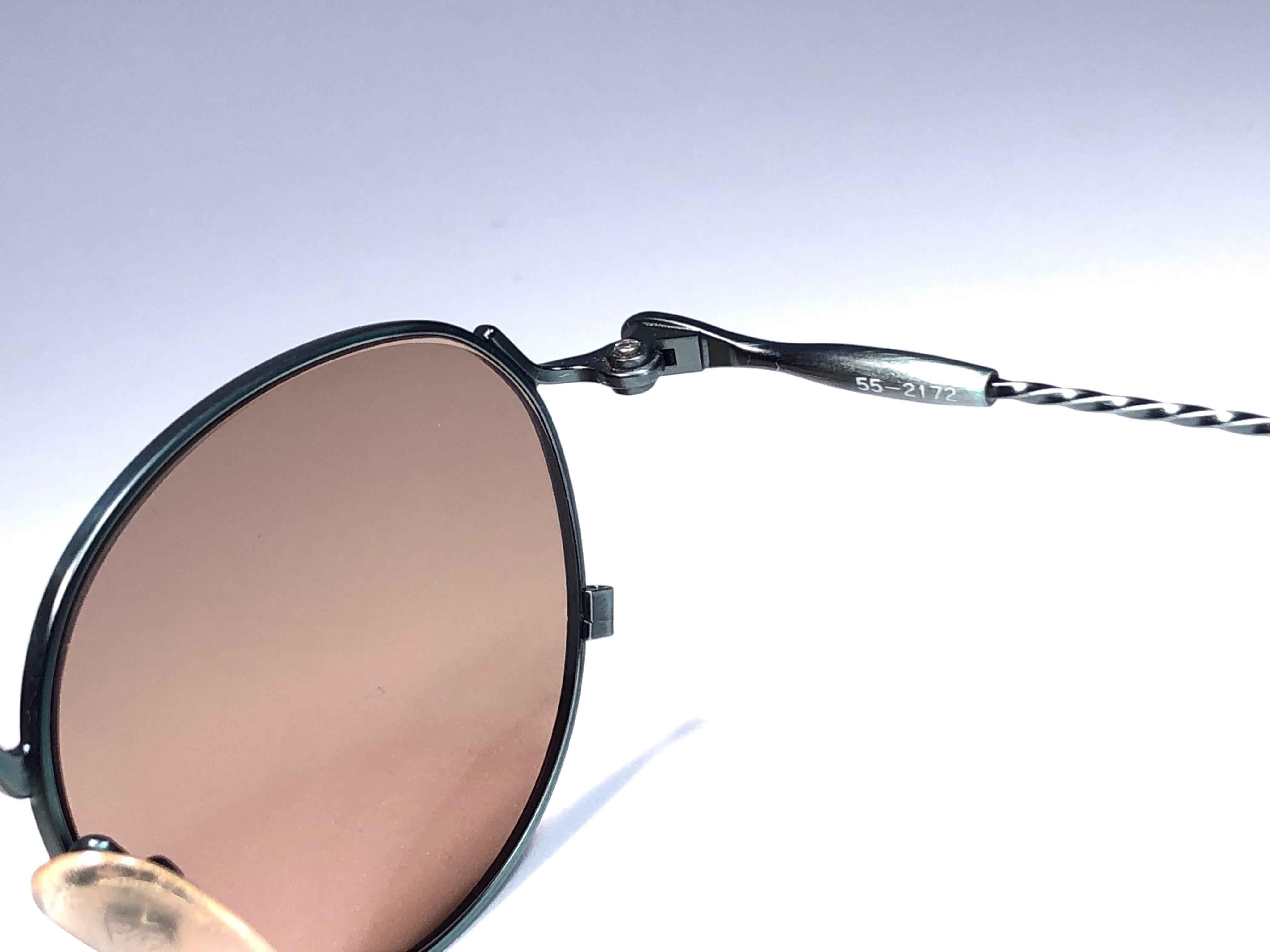 &New Jean Paul Gaultier Sonnenbrille mit grünem Metallrahmen.
Goldfarbene, verspiegelte Gläser, die einen tragbaren JPG-Look vervollständigen.

Erstaunliches Design mit starken, aber raffinierten Details.
Design und Herstellung in den 1990er
