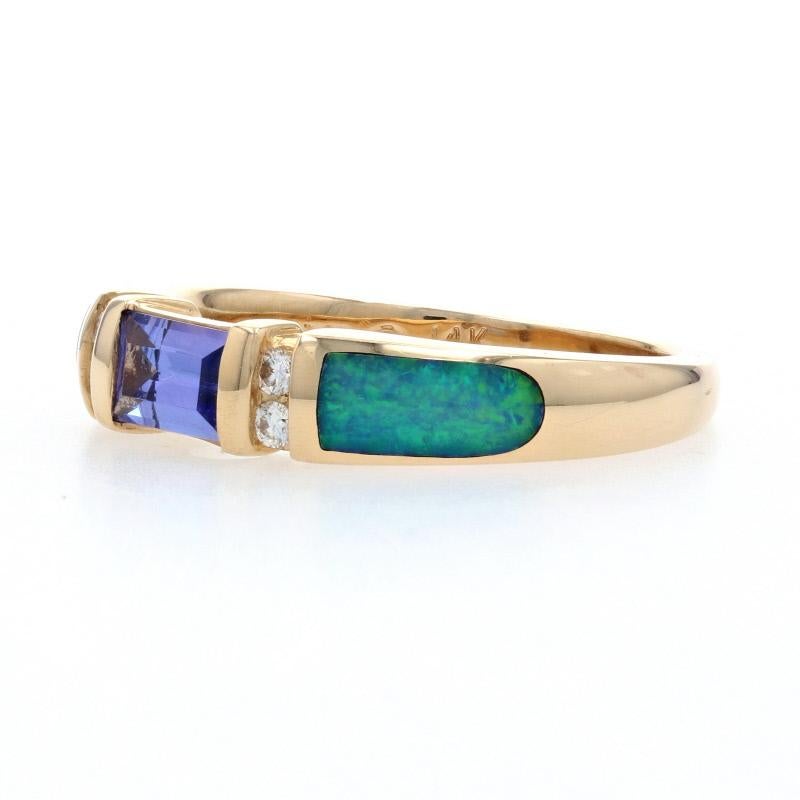 The essence of elegance, this designer ring would be a wonderful gift for any special occasion. This NEW Kabana piece is fashioned in classic 14k yellow gold and features a bezel-set tanzanite bordered in diamonds. Inset opals adorn the sides of the