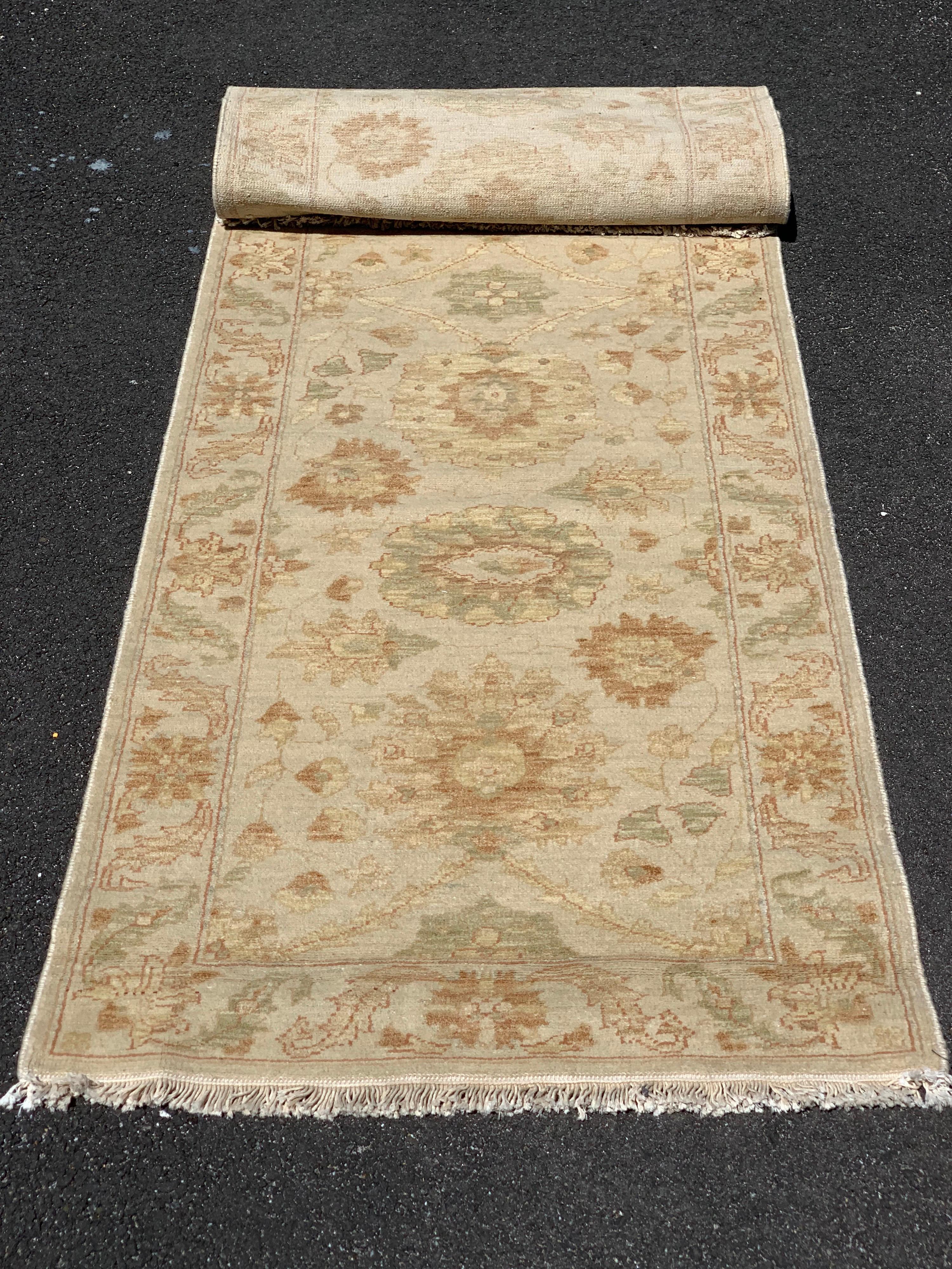This is a new late 20th century long and narrow beige ivory floral Persian style runner rug handwoven in Alexandria, Egypt in 1990s. We manufactured these rugs and the design and colors were hand chosen by us and we have a wide variety of sizes in