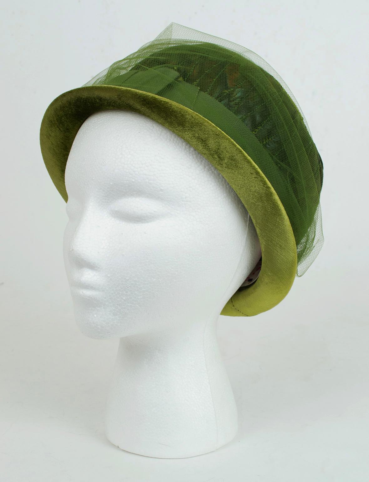 From its gemstone color to its iridescent green feathers to its feminine tulle covering, this cloche drips with artistic mid-century details. Most ingeniously, it features a removable gathered tulle band that fastens with hat pins so it is
